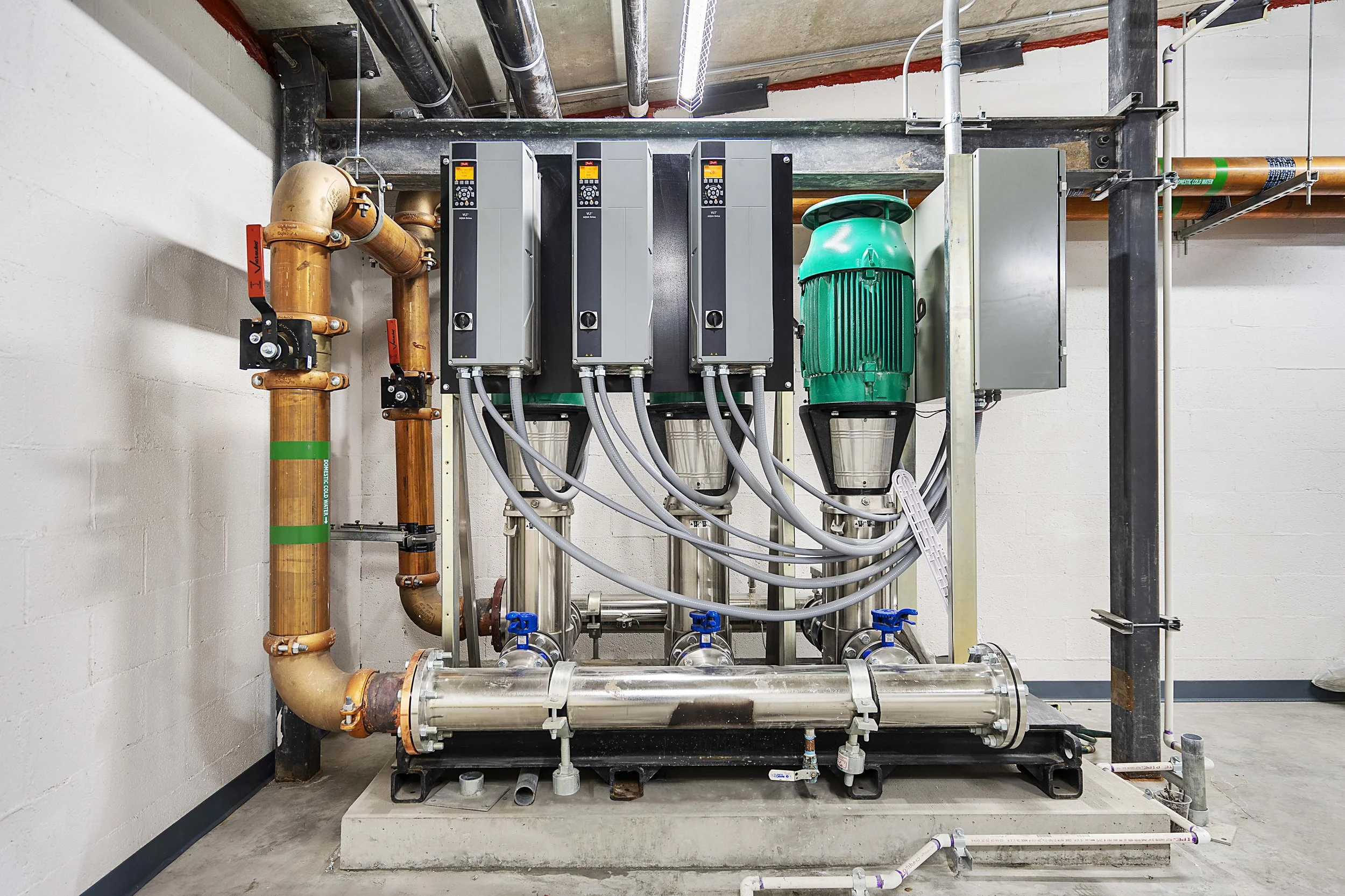 Industrial mechanical equipment with pipes, valves, and control units in a utility room.
