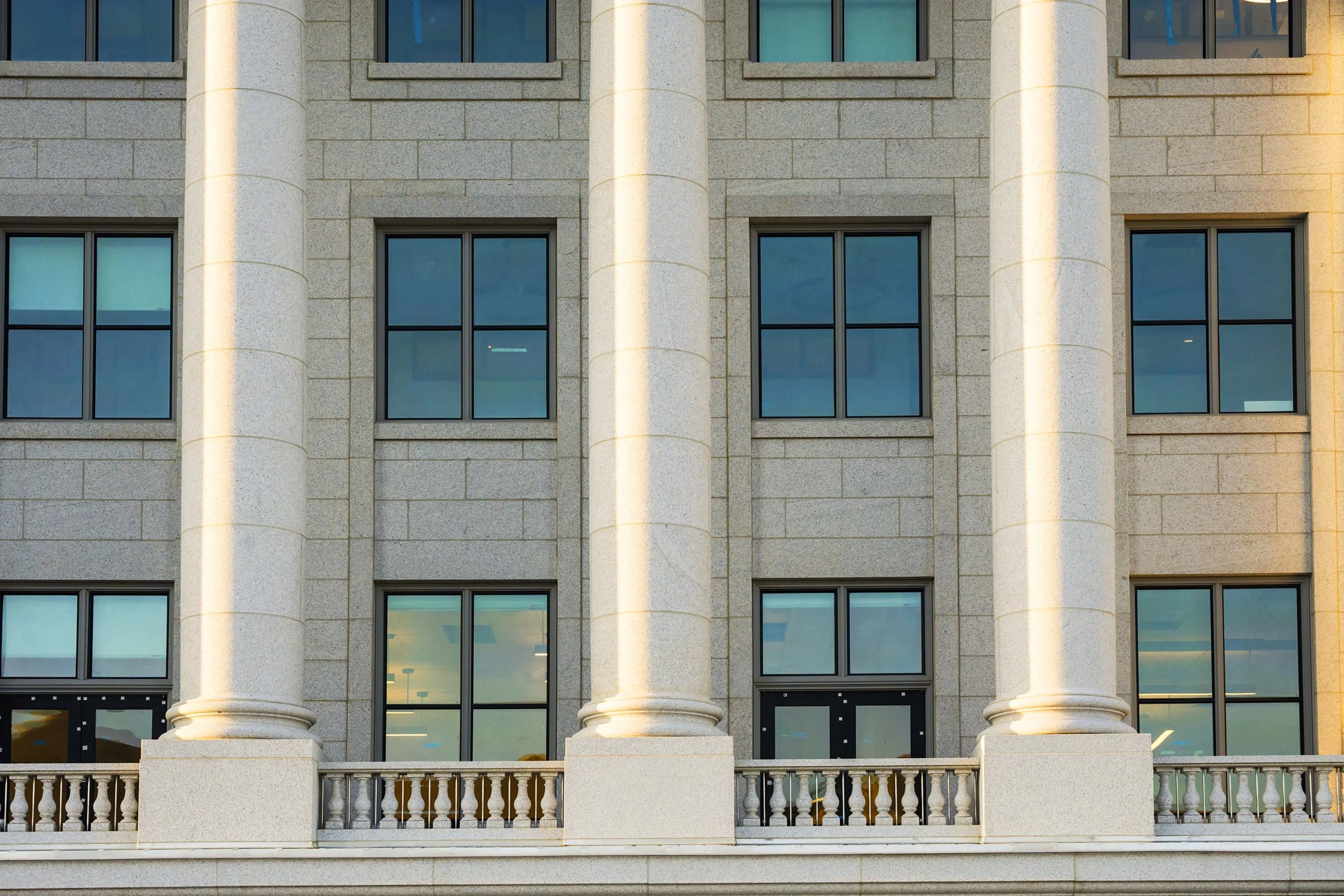 Facade of a modern building with large columns and multiple Manhattan style windows