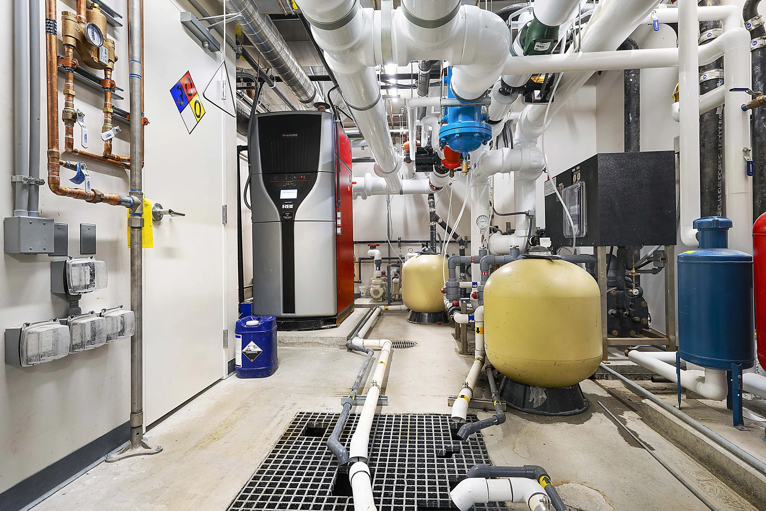 Industrial mechanical room with pipes, tanks, meters, and machinery for building systems