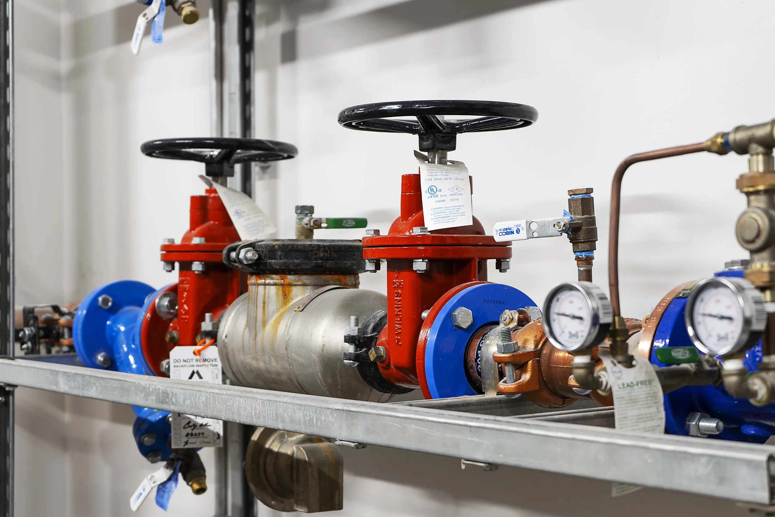 Industrial piping system with gauges, valves, and motors mounted on a metal shelf.