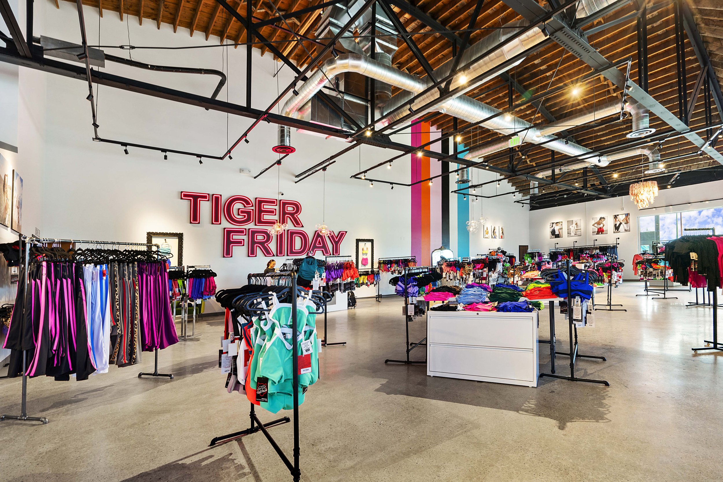 Inside a retail store displaying athletic wear with a large neon sign that says "TIGER FRIDAY" on the wall.