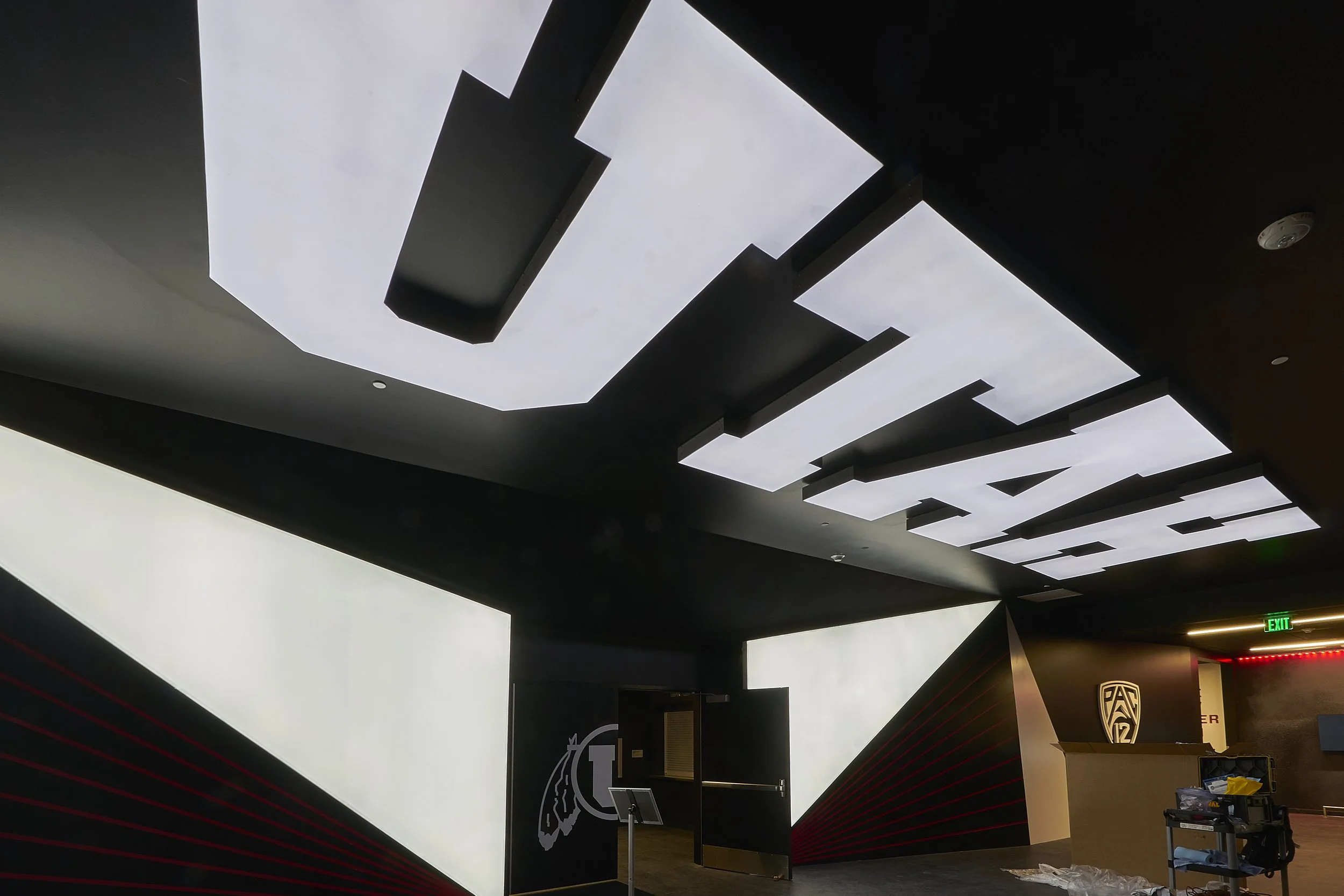 Interior of a modern sports facility or stadium with a black and white color scheme, featuring geometric ceiling designs and sports team logos on the walls.