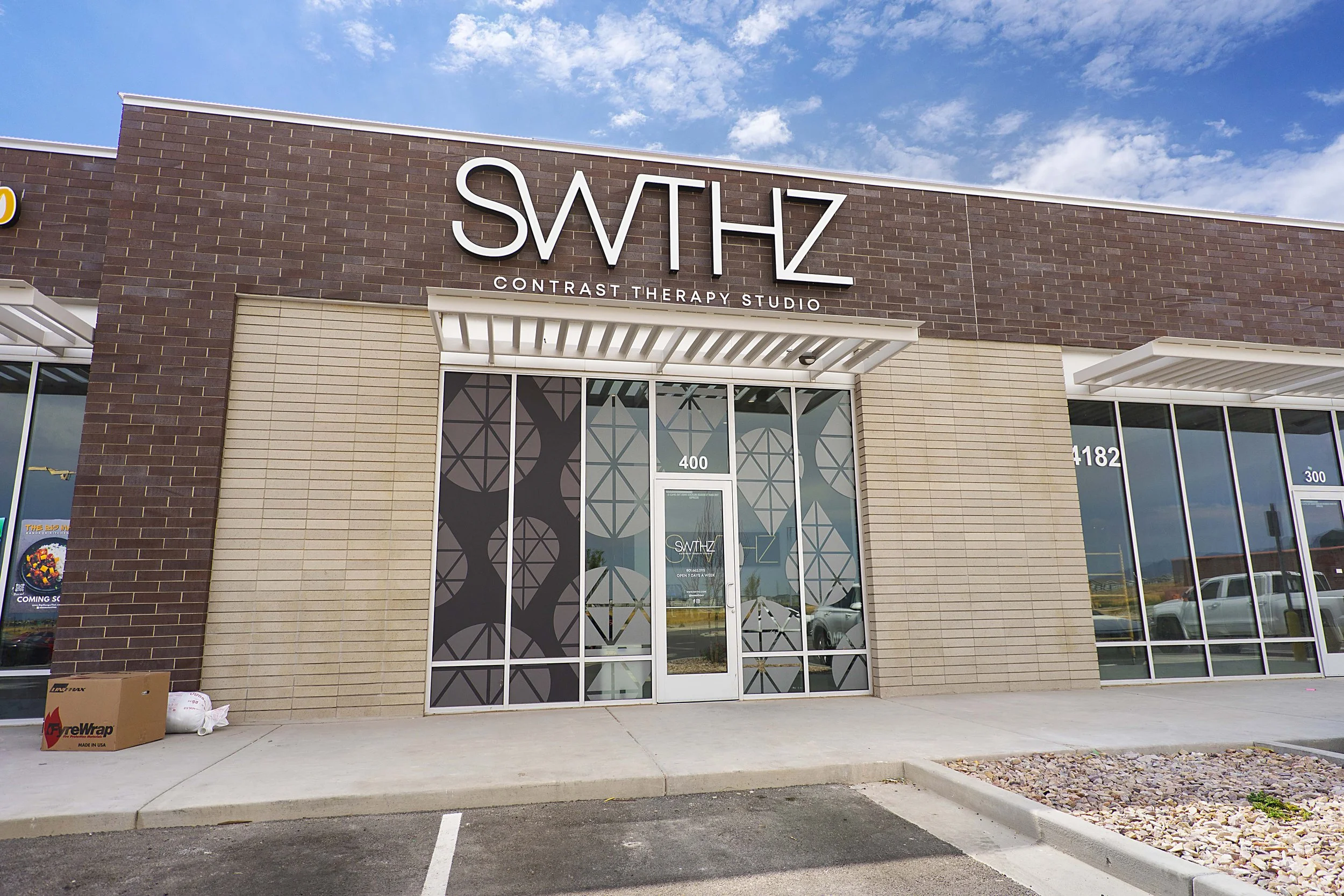 Exterior view of SWTHZ Contrast Therapy Studio storefront with glass windows and a sign above the entrance reading 'SWTHZ' and 'Contrast Therapy Studio'.