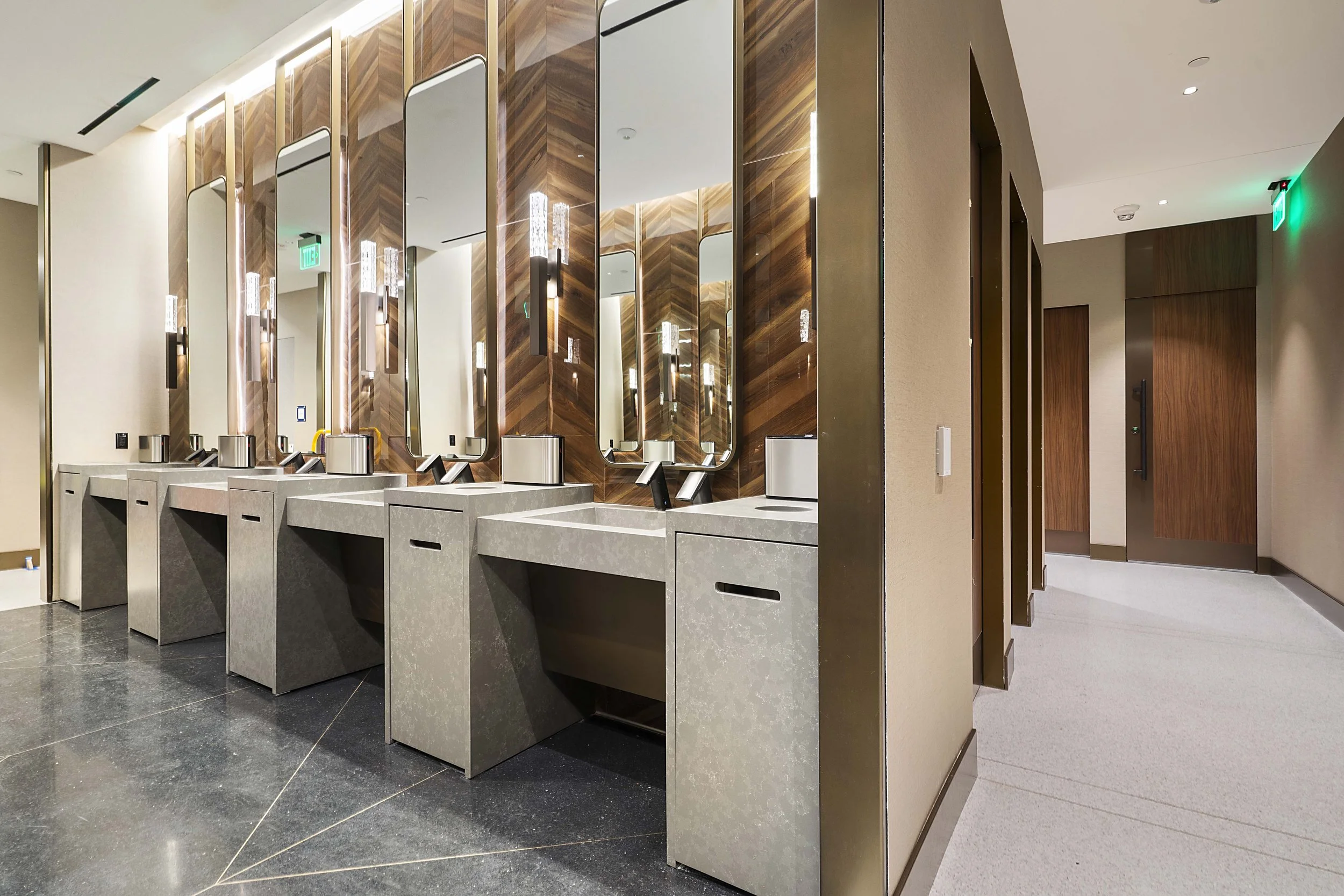 Public restroom with multiple sinks, mirrors, and modern lighting fixtures