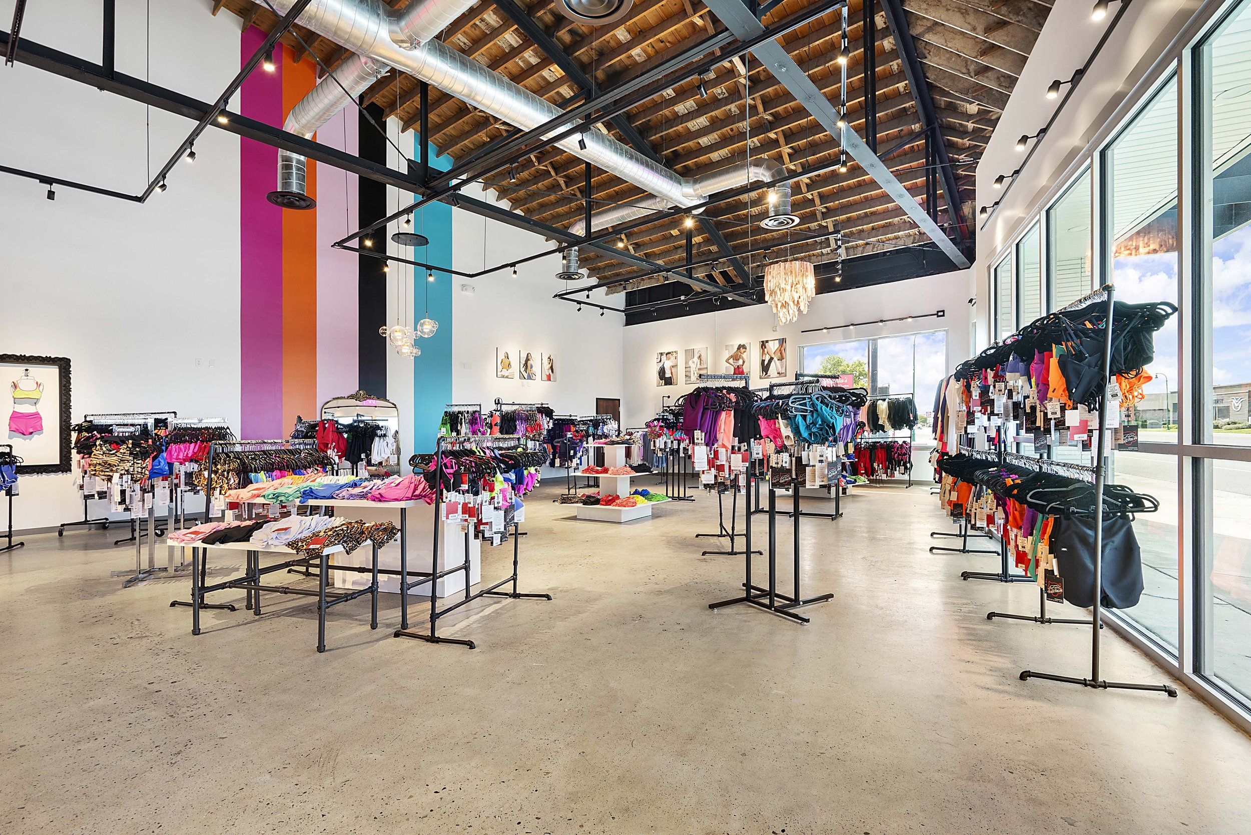 Clothing store interior with racks of colorful swimwear and athletic wear near large windows