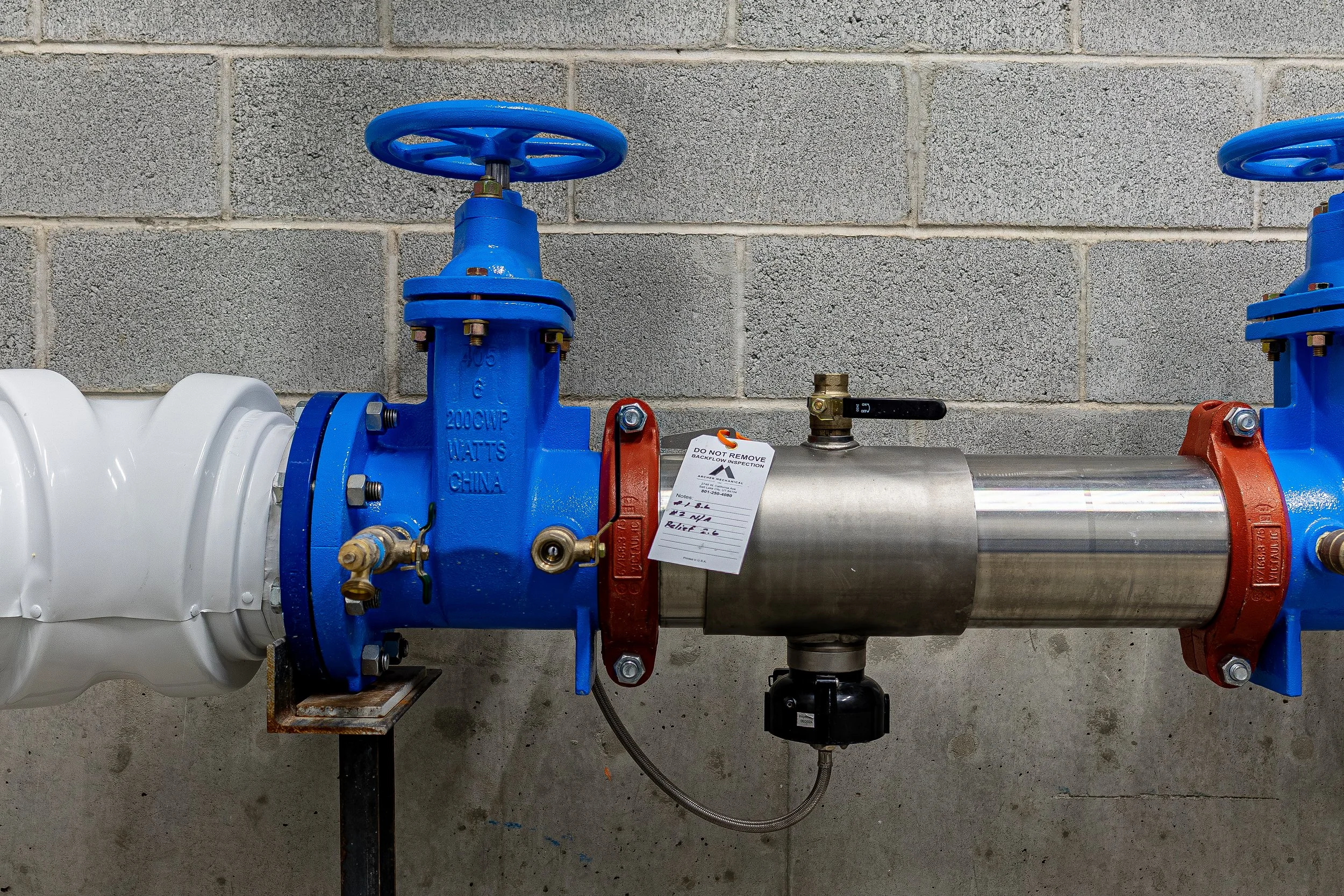 Industrial pipe system with blue valves on a concrete wall.