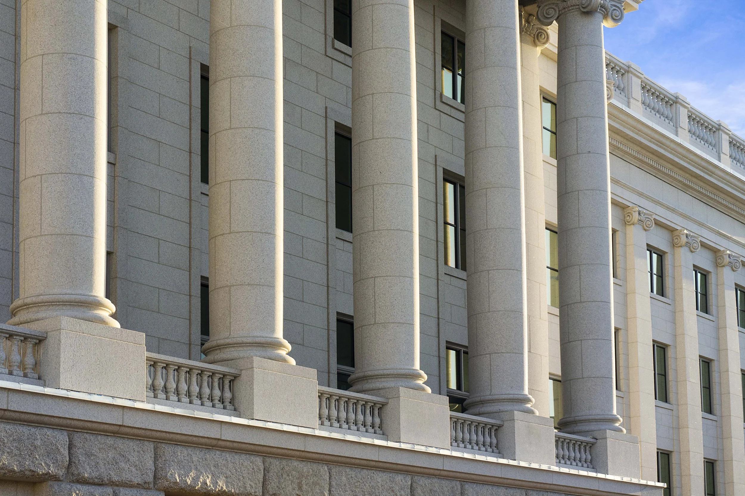 Close-up of a classical-style government or institutional building with large stone columns, ornate molding, and multiple rectangular windows.