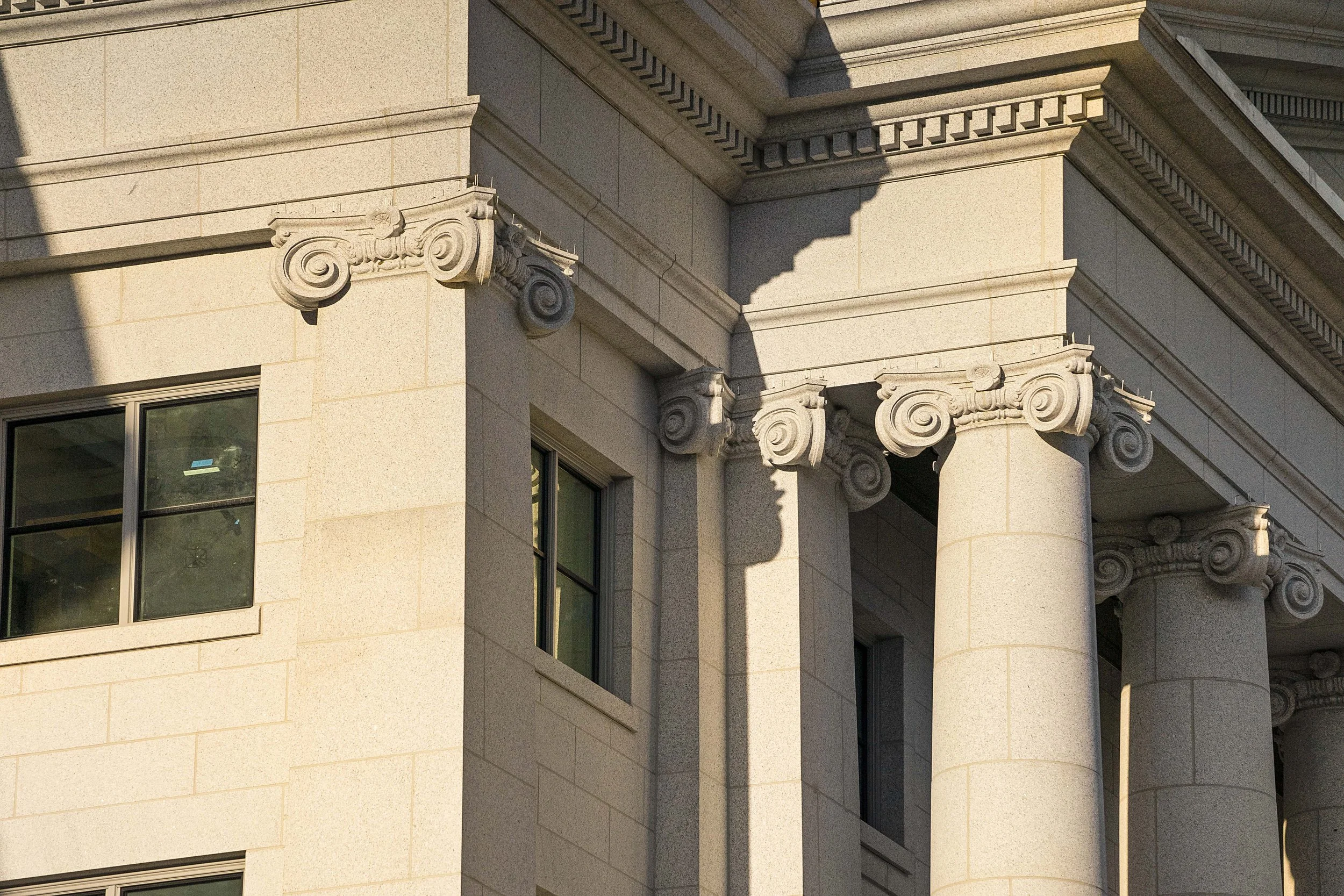 Close-up of the corner of a classical stone building with decorative columns and windows.