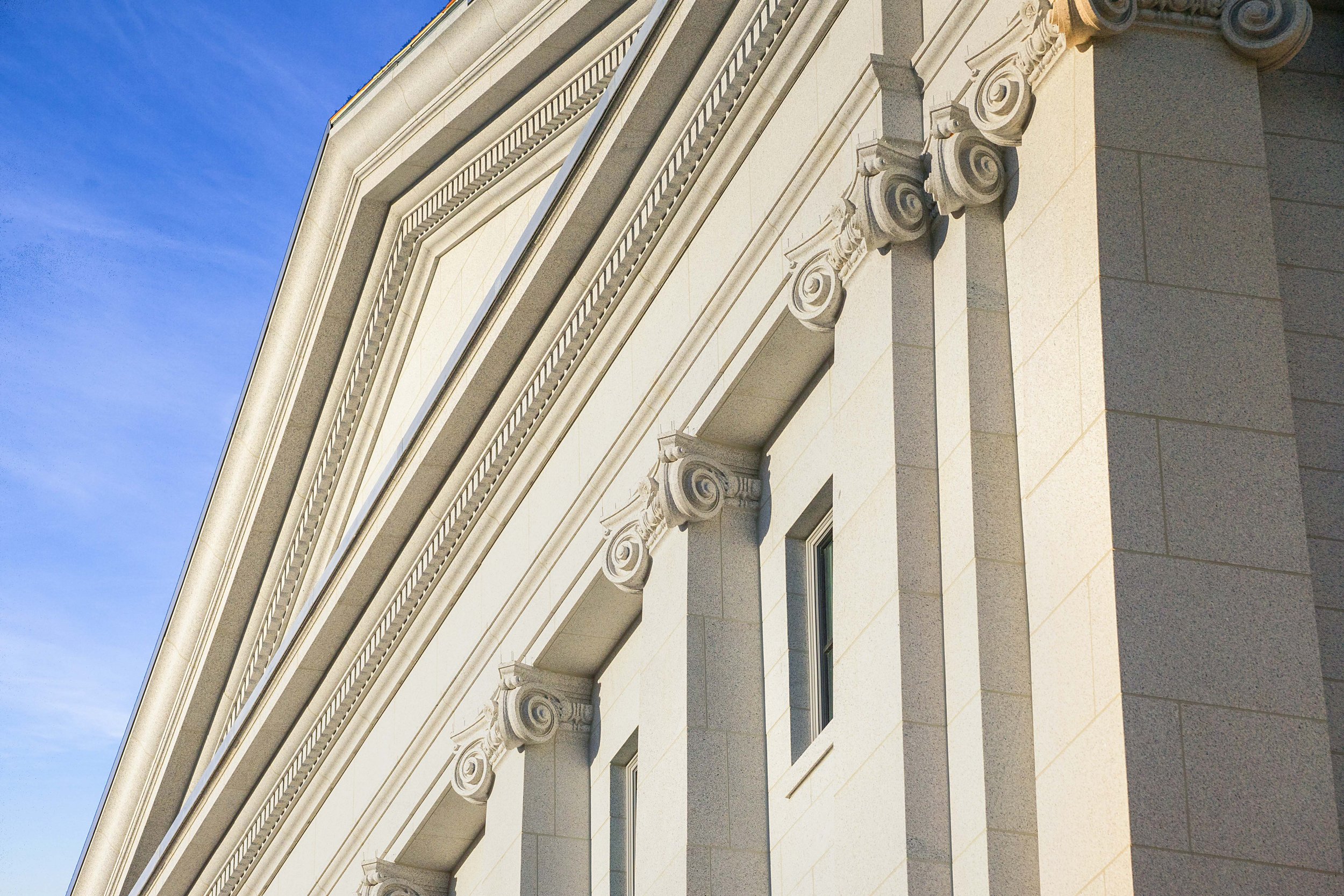 Close-up of a classical building facade with decorative columns and detailed molding against a blue sky.