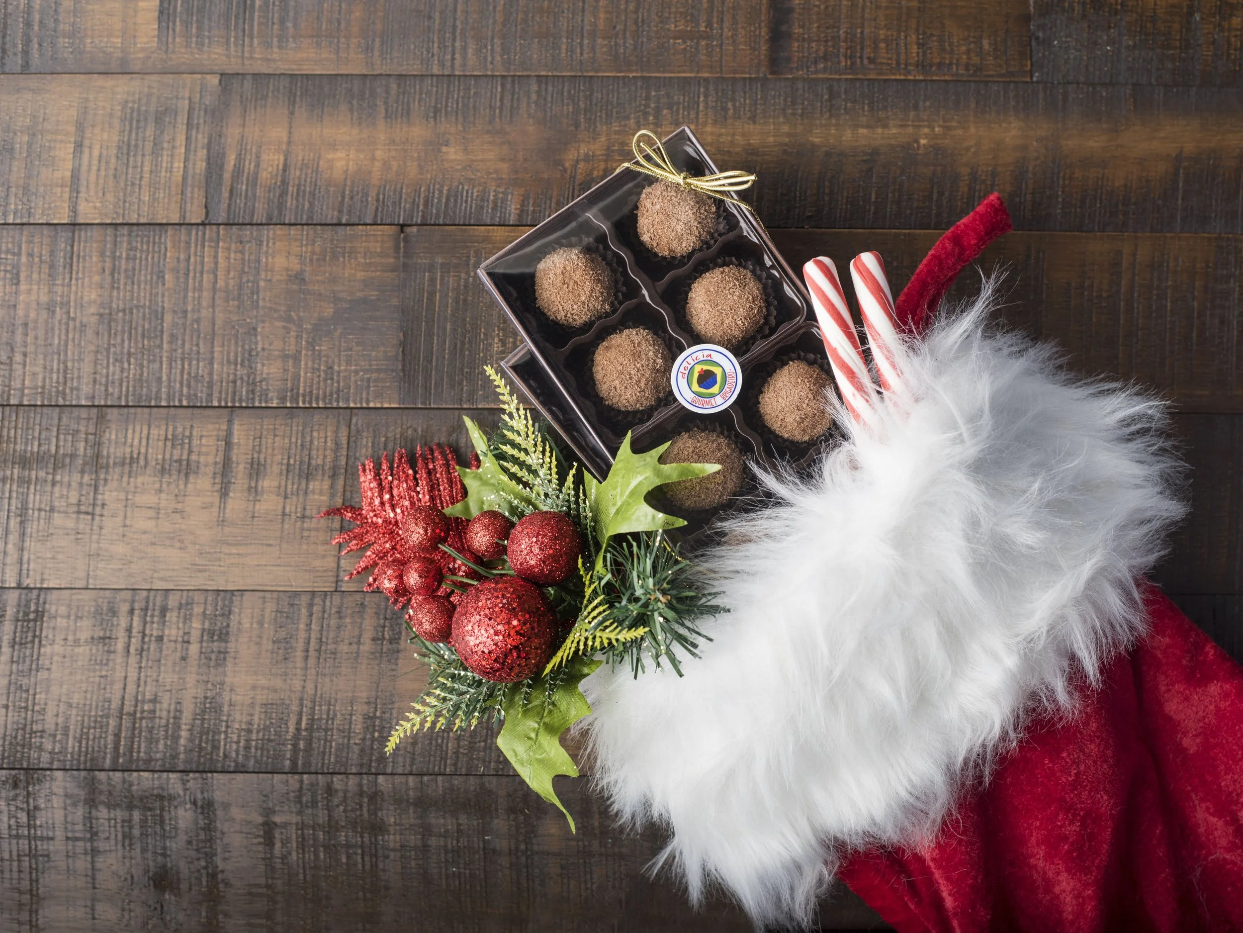 Christmas stocking with chocolate truffles, candy canes, and festive decorations on a wooden surface.