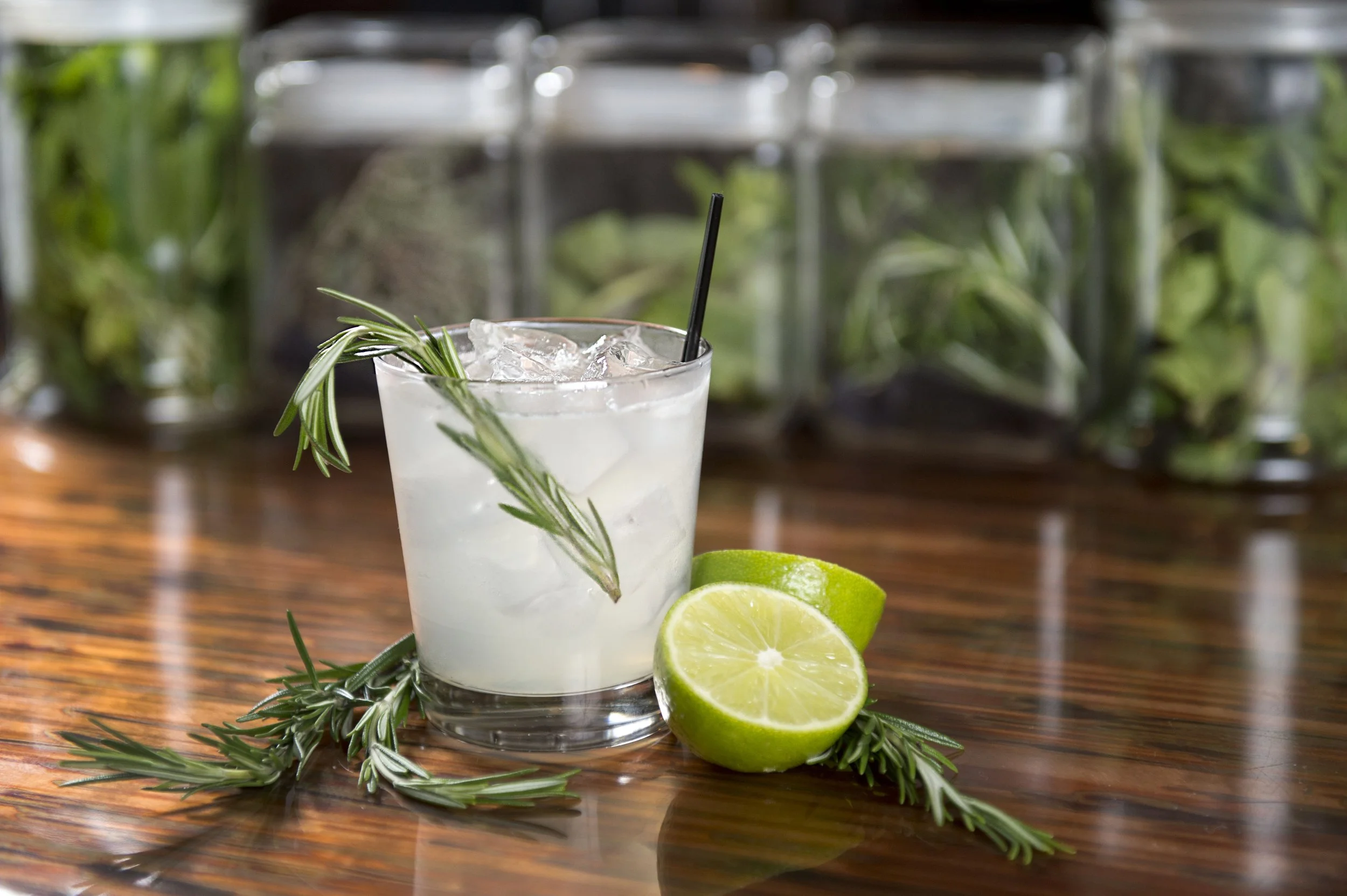 Cocktail with rosemary and lime on wooden table.