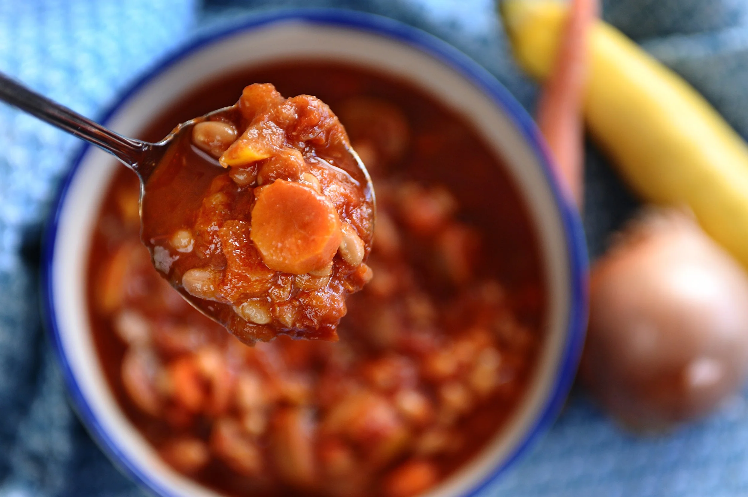 Spoonful of vegetable soup with carrots, beans, and tomato sauce.