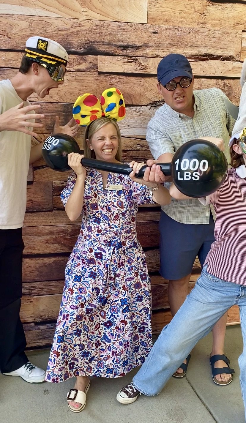 A woman in a sequined dress posing in front of a shimmering backdrop, with a photo booth camera in the foreground.