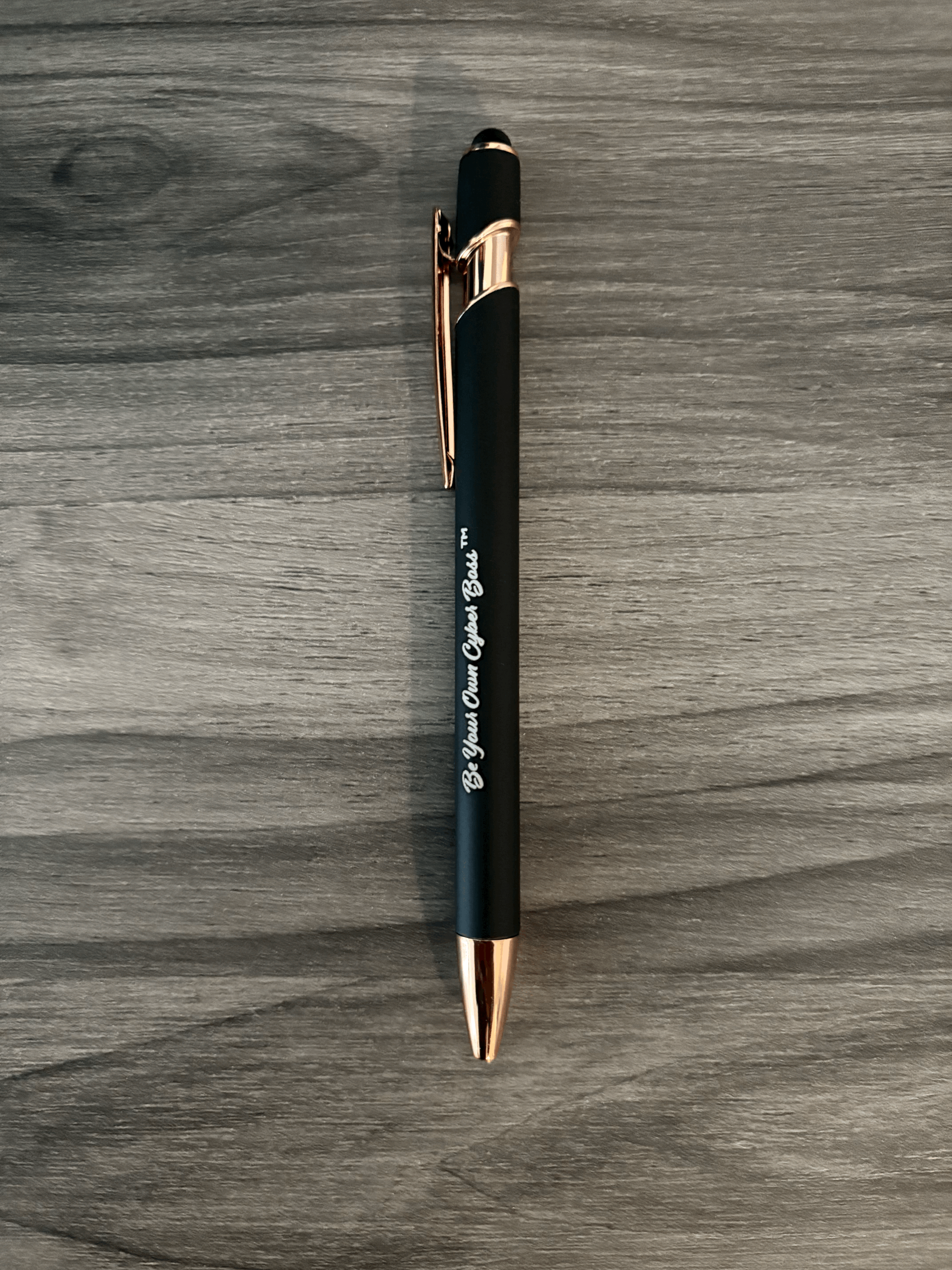 Close-up of the black Cyber Boss™ pen featuring the ‘Be Your Own Cyber Boss™’ engraving with rose-gold accents.