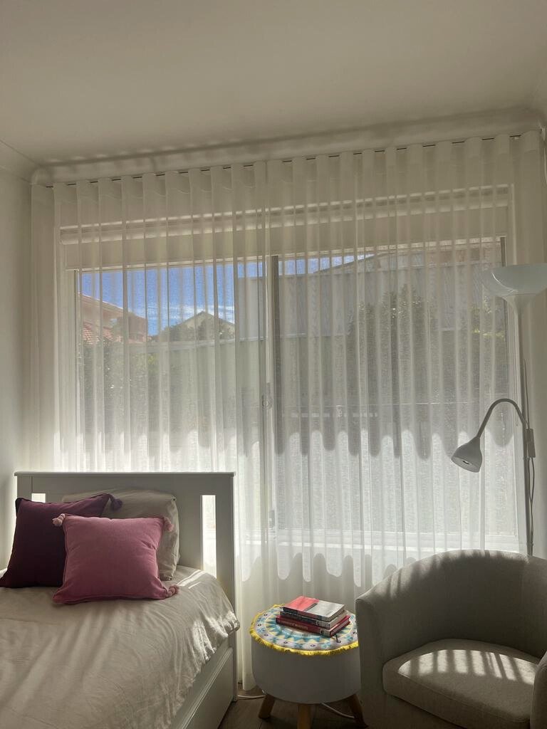 Sunlit bedroom with sheer curtains