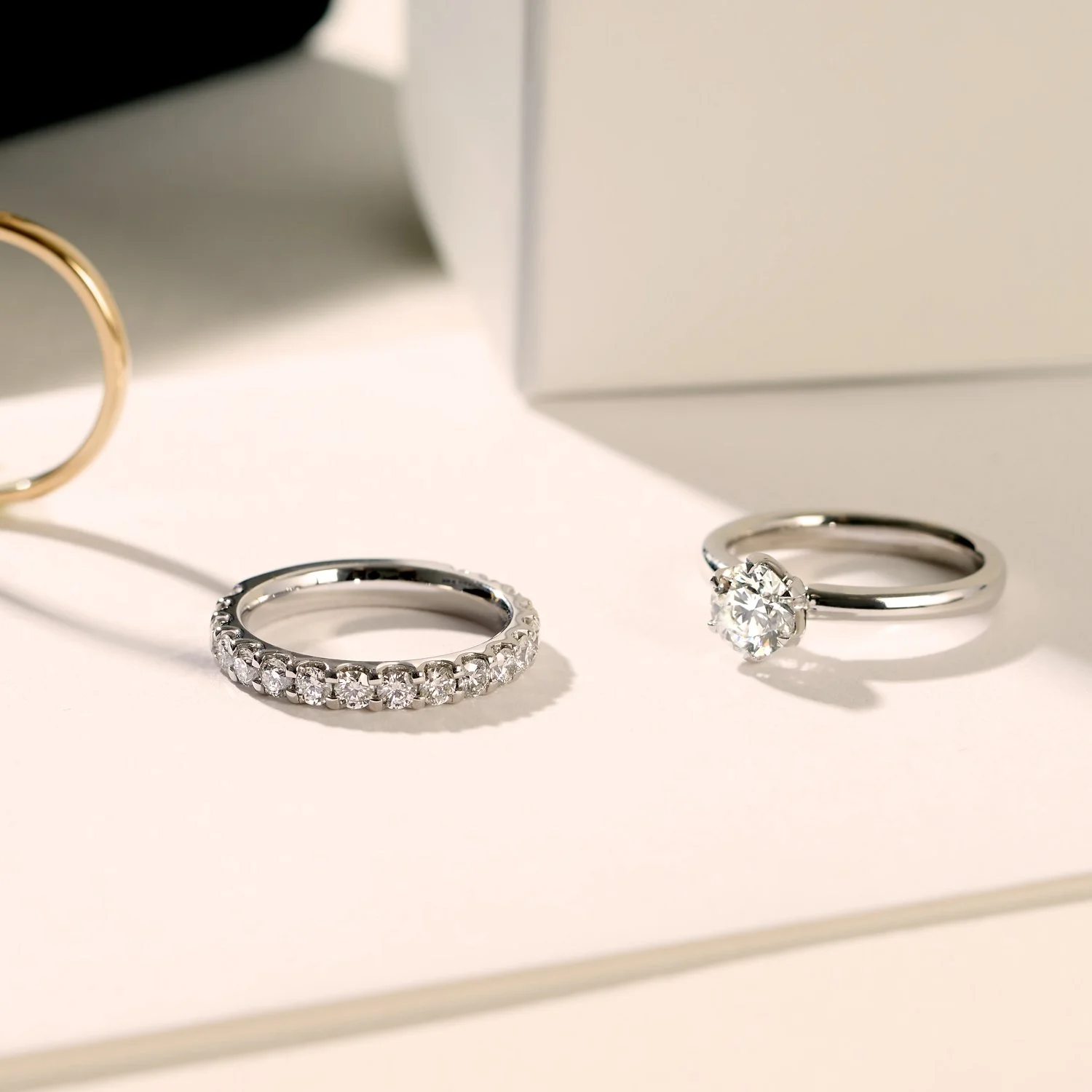 A commercial jewellery editorial photograph of two silver rings with large clear gemstones resting on a white surface, with a white box . The image was taken by Tom MacDonald in Brisbane for Hardey Brothers Jewellers