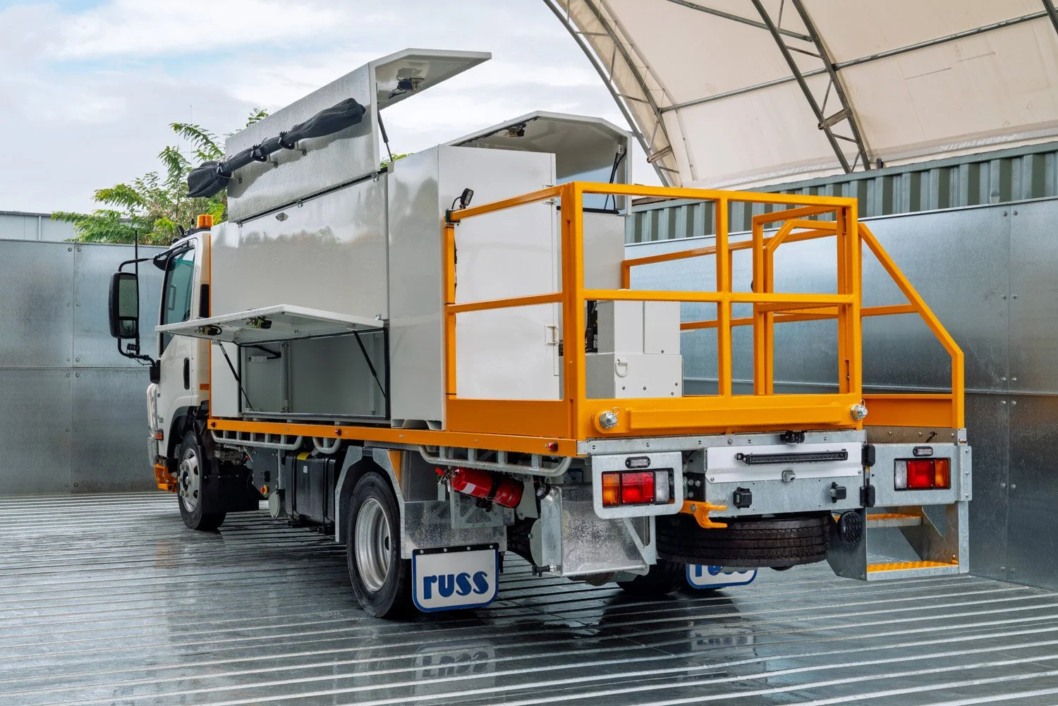  A photograph taken by Brisbane based Tom MacDonald of Tom Mac photography, of a Utility truck with equipment storage and orange safety railings, parked inside a covered area.