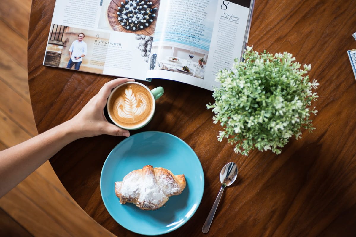 A commercial photograph of a person holding a coffee mug with latte art. Taken by Brisbane based commercial photographer tom MacDonald. 