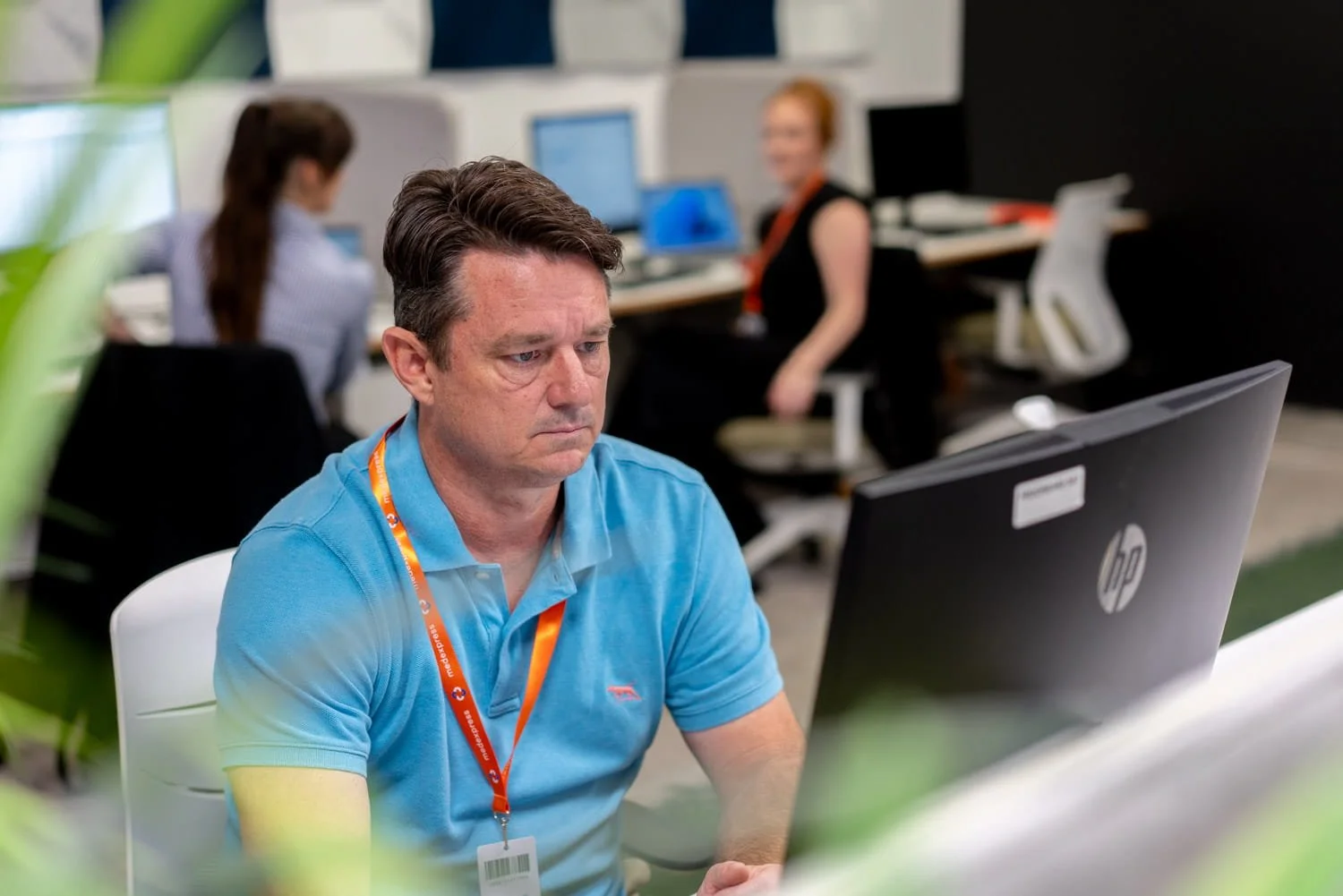 A young man sitting in front of a computer in an office, taken by commercial photographer Tom MacDonald of Tom Mac photography