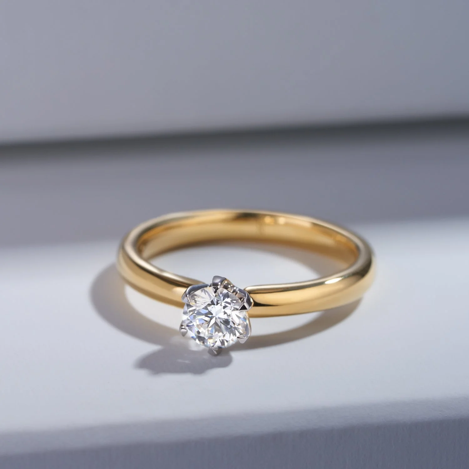 A  commercial jewellery photograph of a gold ring with a diamond solitaire setting on a grey background taken by Brisbane based commercial photographer Tom MacDonald for Hardy brothers jewellers.
