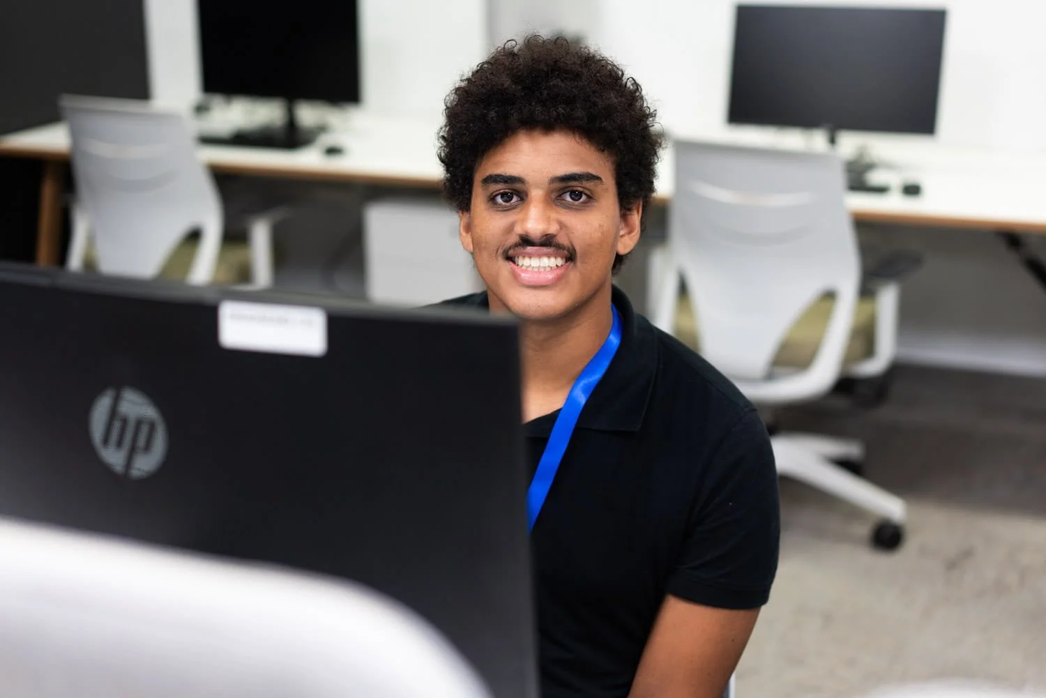 A young man sitting in front of a computer in an office, taken by commercial photographer Tom MacDonald.