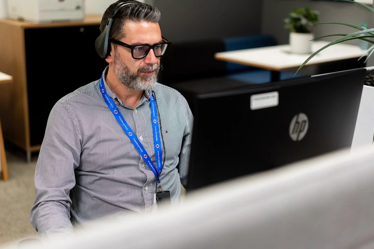A commercial image of a man sitting in front of a computer in an office, taken by commercial photographer Tom MacDonald of Tom Mac photography
