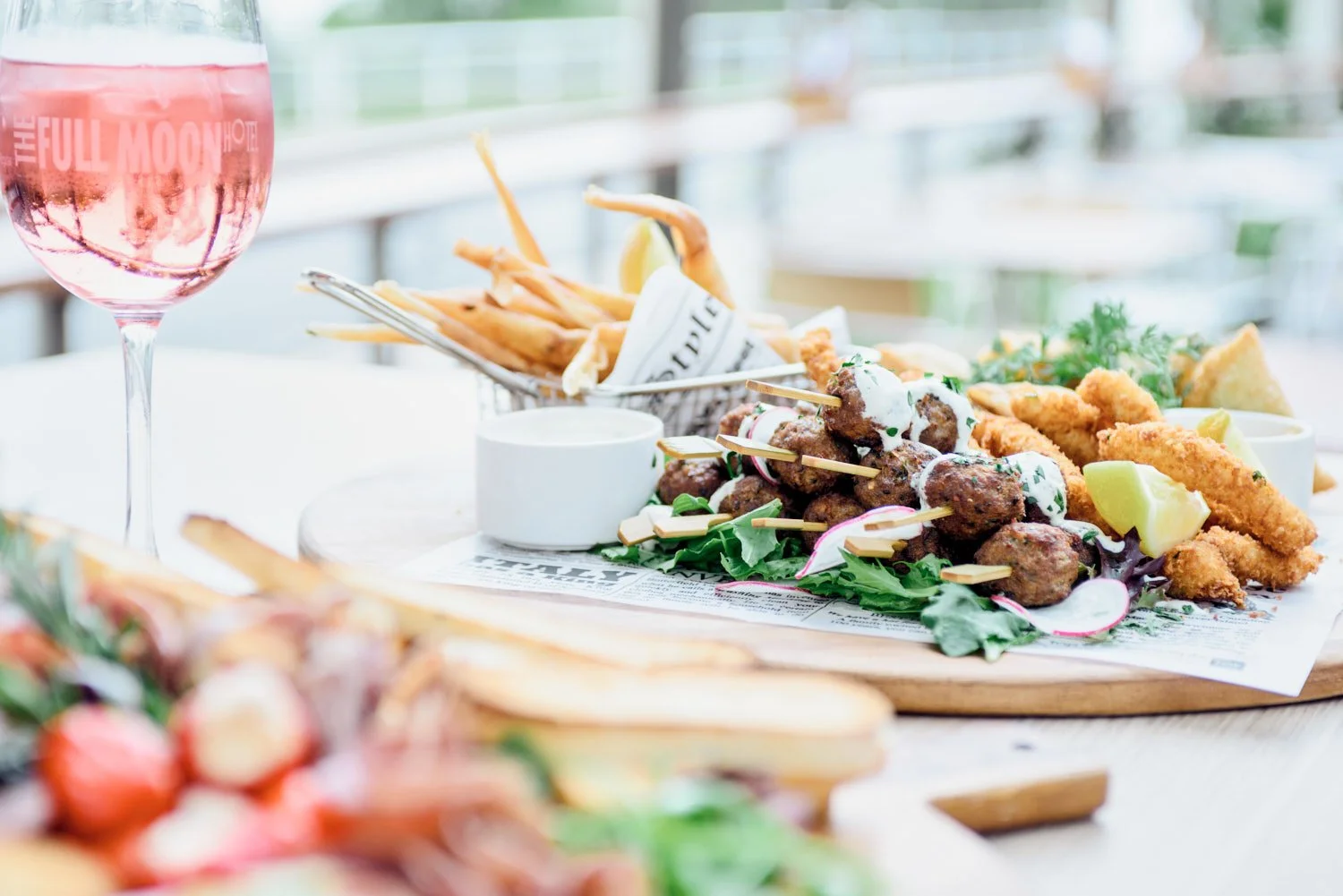 A commercial food image taken by Brisbane based commercial food photographer Tom MacDonald of a plate of skewered meatballs with white sauce, lemon wedges, and greens.
