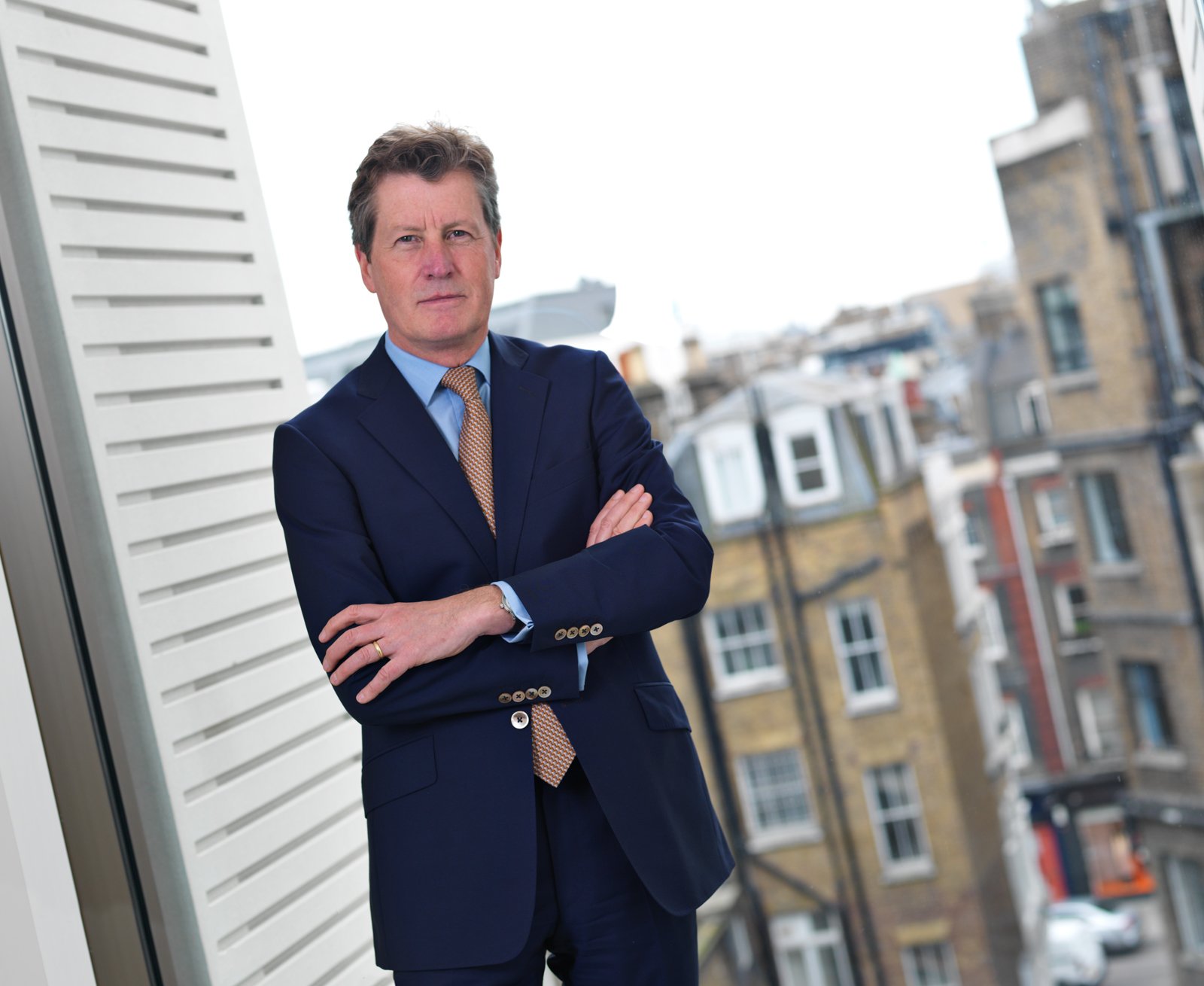A commercial portrait of a businessman infront of a window showing the city. Taken by Tom MacDonald