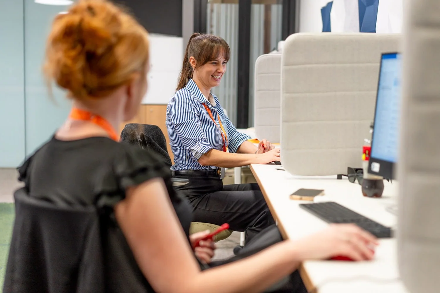 A  ciommercial photograph of  a woman sitting in front of a computer in an office, taken by commercial photographer Tom MacDonald of Tom Mac photography.