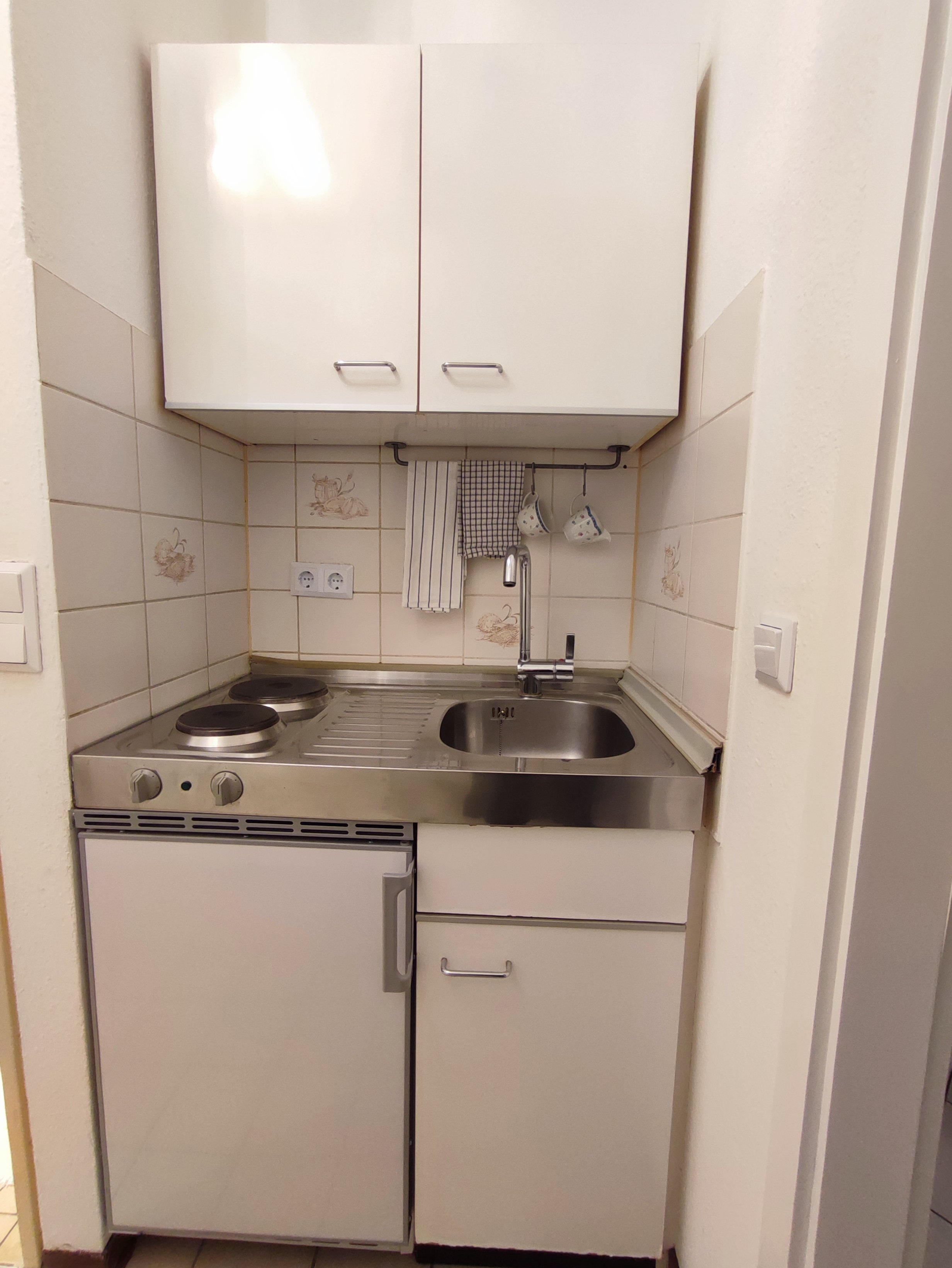 Kompakte Pantry-Küche ausgestattet mit reichlich floral gemustertem Geschirr.