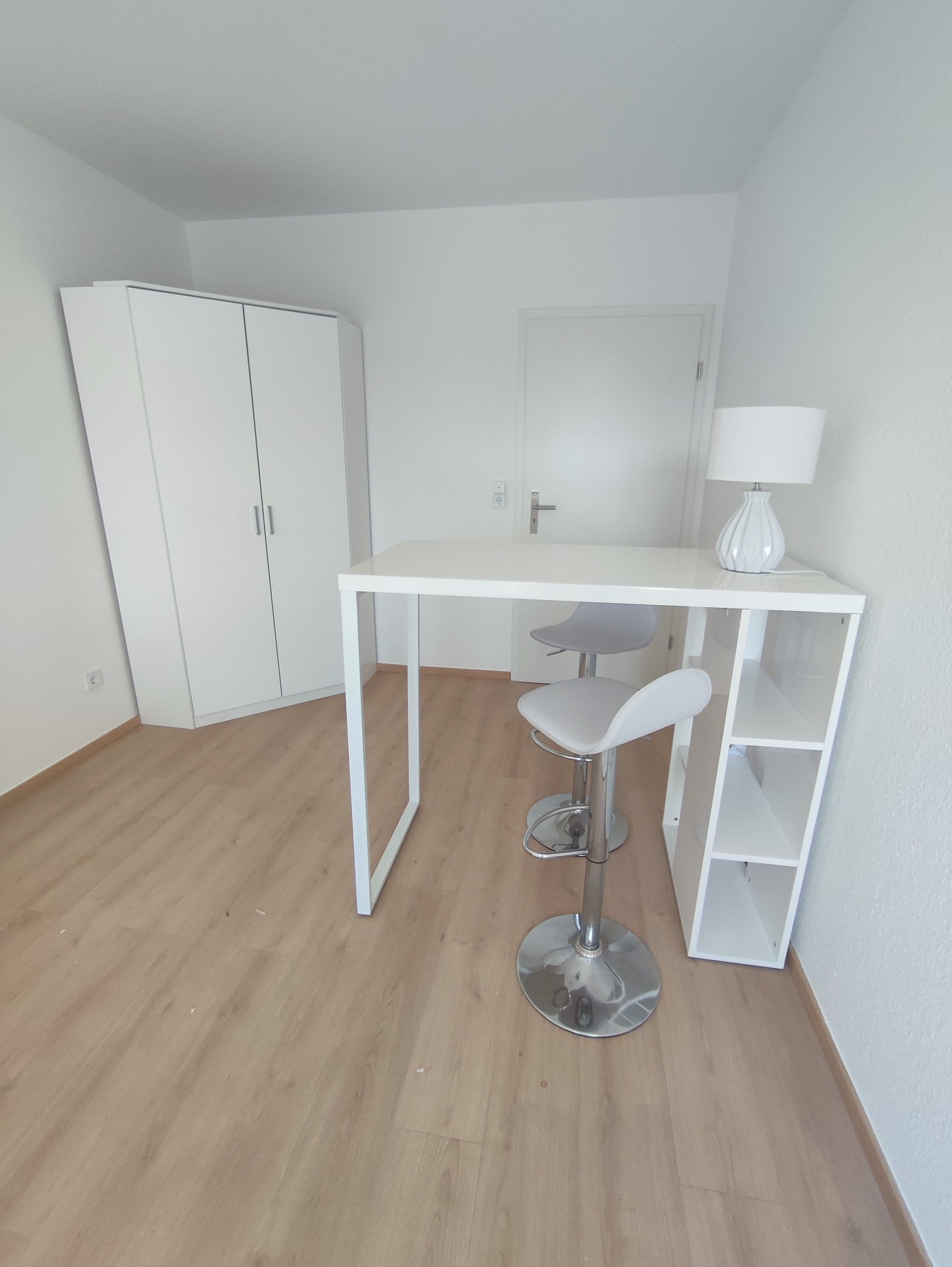 Wohnraum mit Hochtisch und Eckkleiderschrank für viel Stauraum.