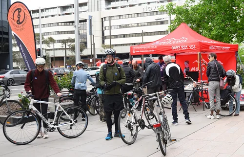 Riders and bicycles beside the red event tent at Veterans Park