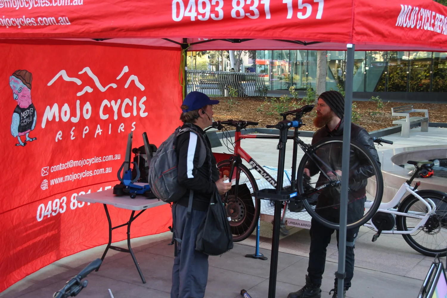 Two people with bicycles at a Mojo Cycles event stall