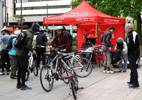 Riders gathering with their bicycles beside the red Mojo Cycles tent at Ride2Work Day 2026