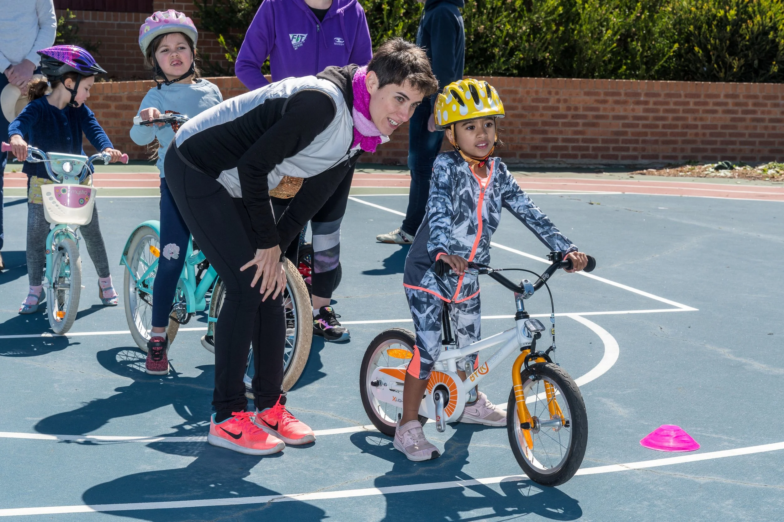 A Pedal Power instructor helping children practise riding their bikes