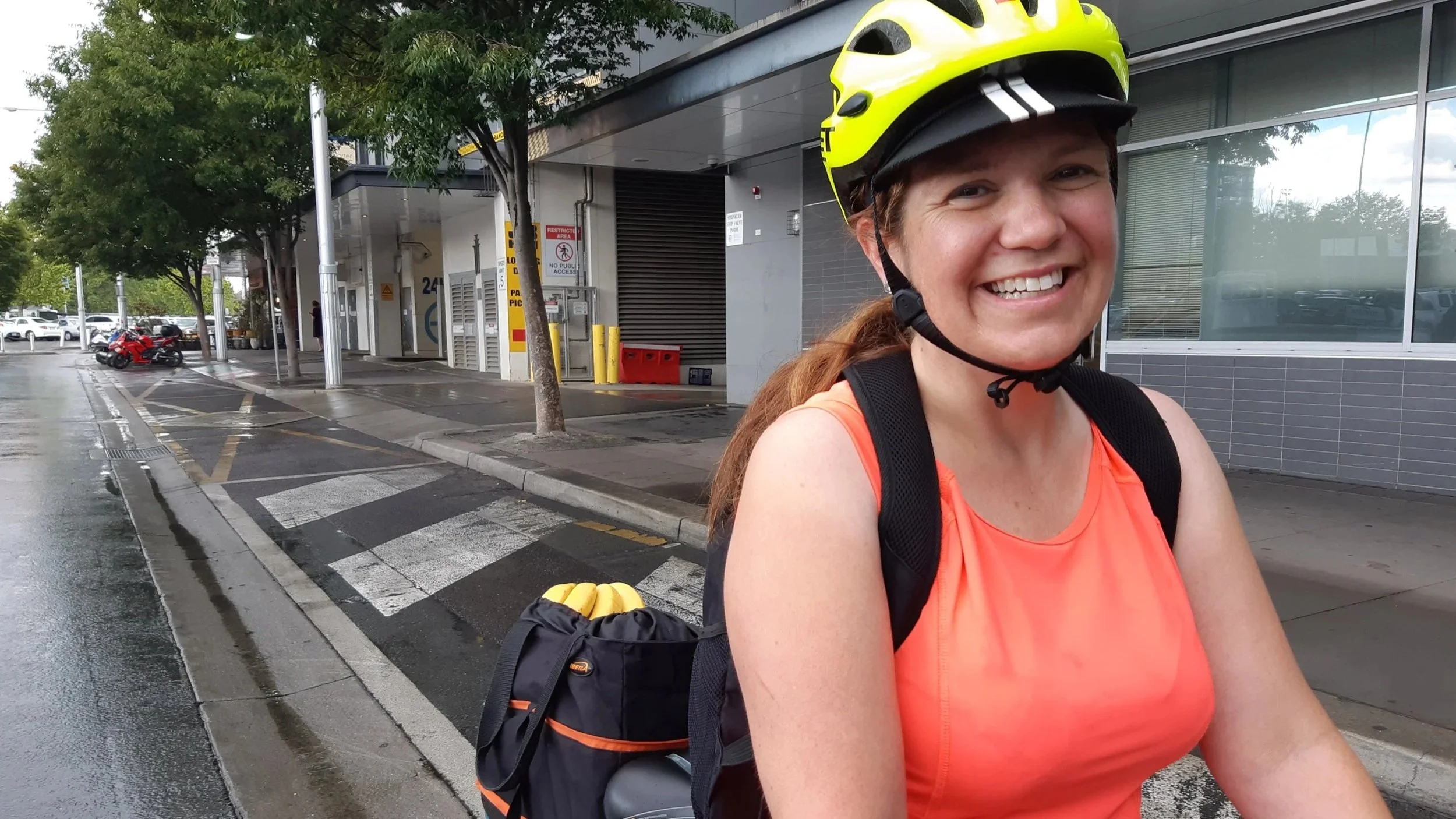 A Pedal Power rider standing beside a bicycle in wet weather