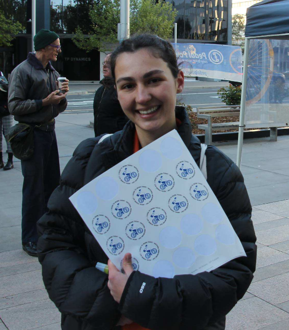 A smiling event attendee holding a sheet of stickers