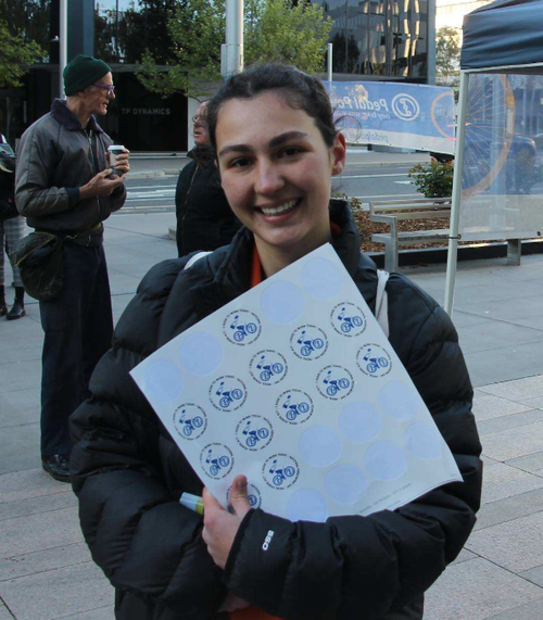 A smiling Ride2Work attendee holding event stickers