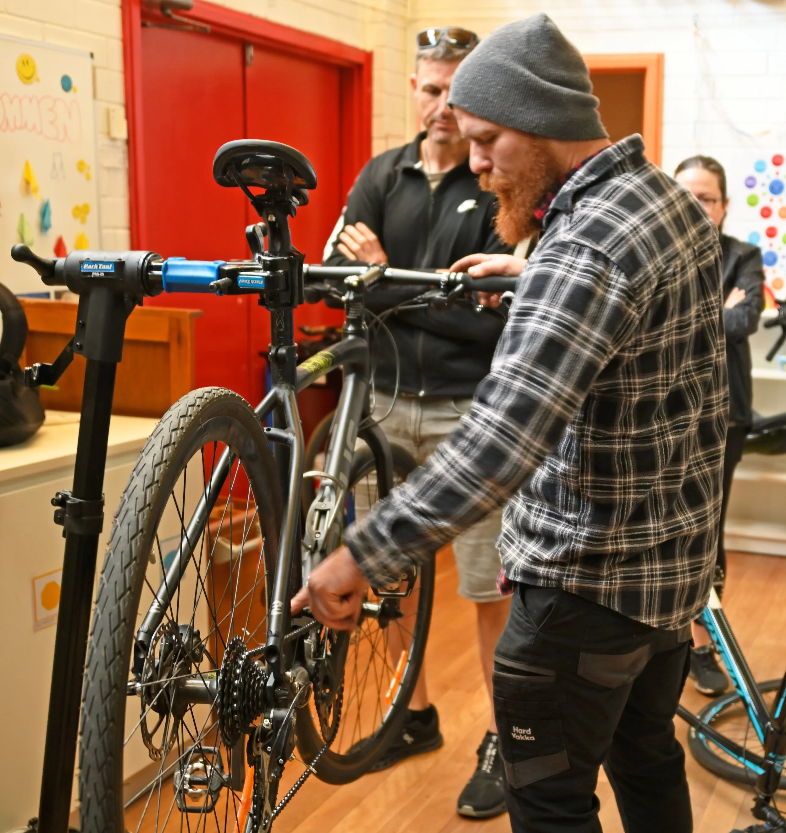 A participant checking components on a bike mounted in a repair stand during a Pedal Power workshop