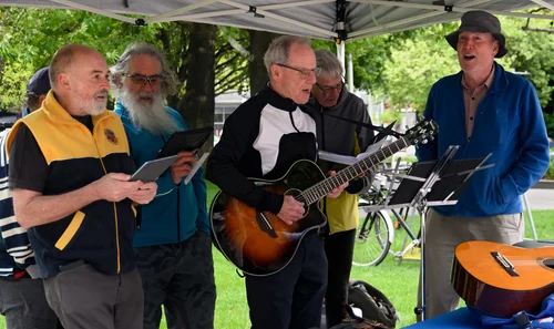 Musicians singing and playing guitar beneath a marquee at Ride2Work Day 2026