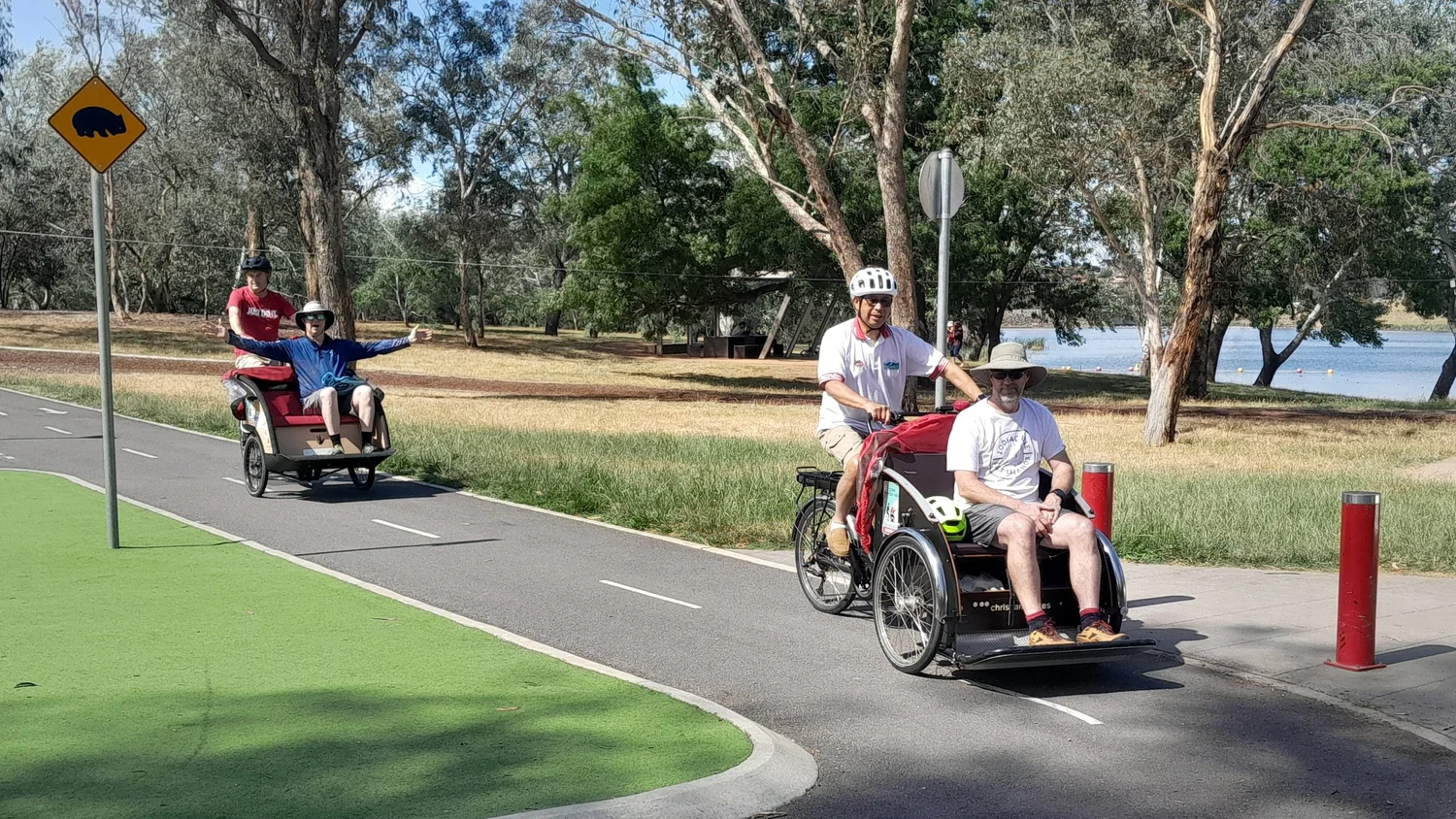Volunteer pilots guiding two trishaws around a gentle bend