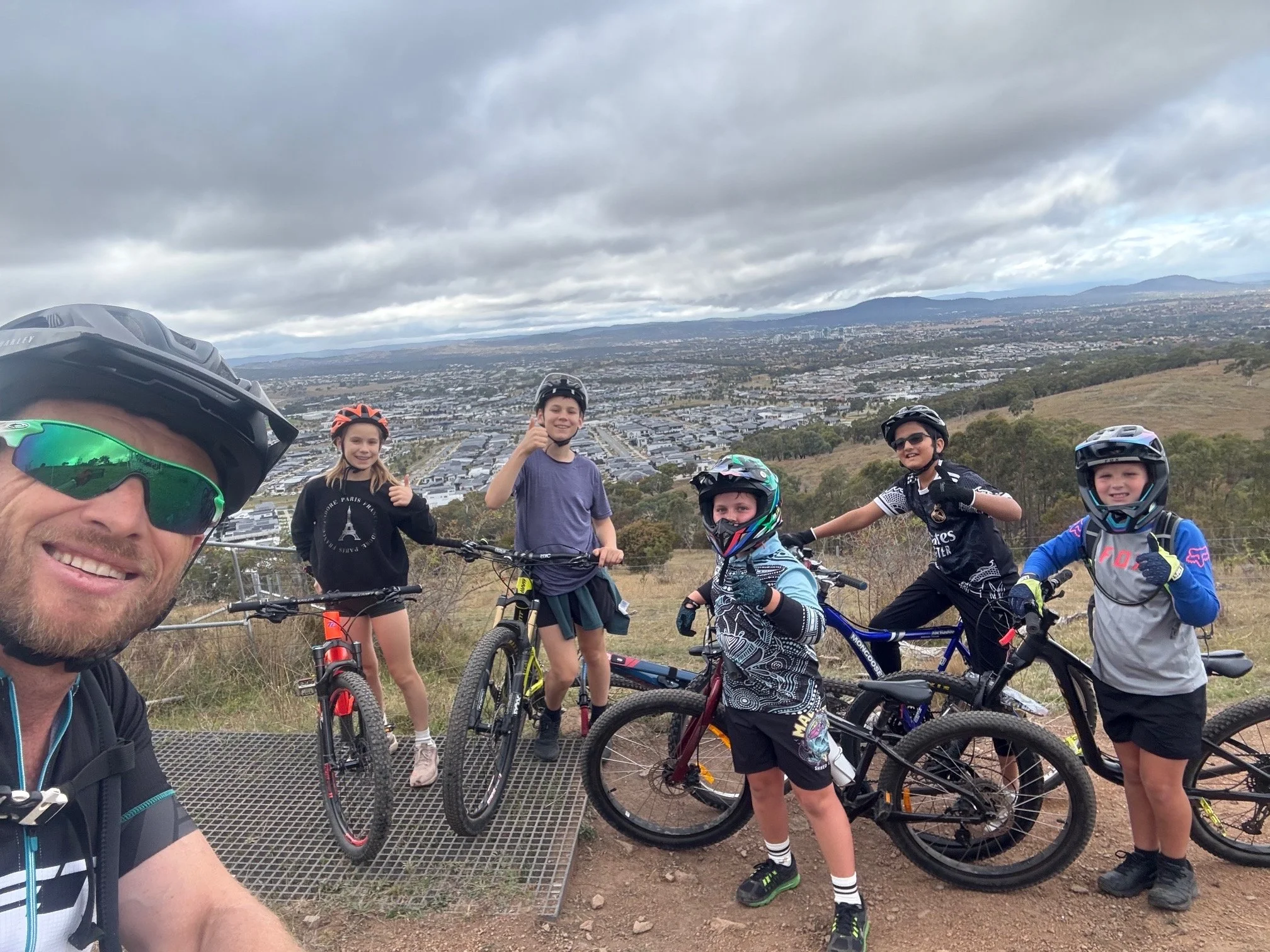 A Pedal Power instructor and young riders with their bikes overlooking Canberra