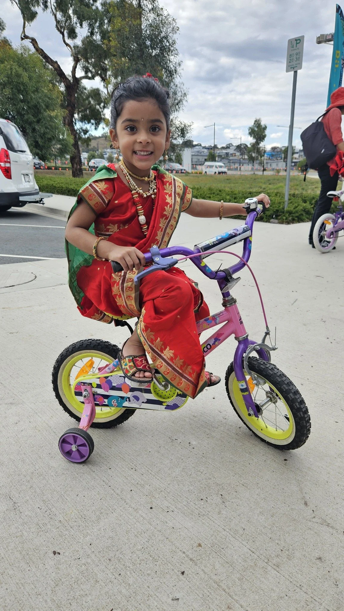A young community member smiling on her Bike Library bicycle