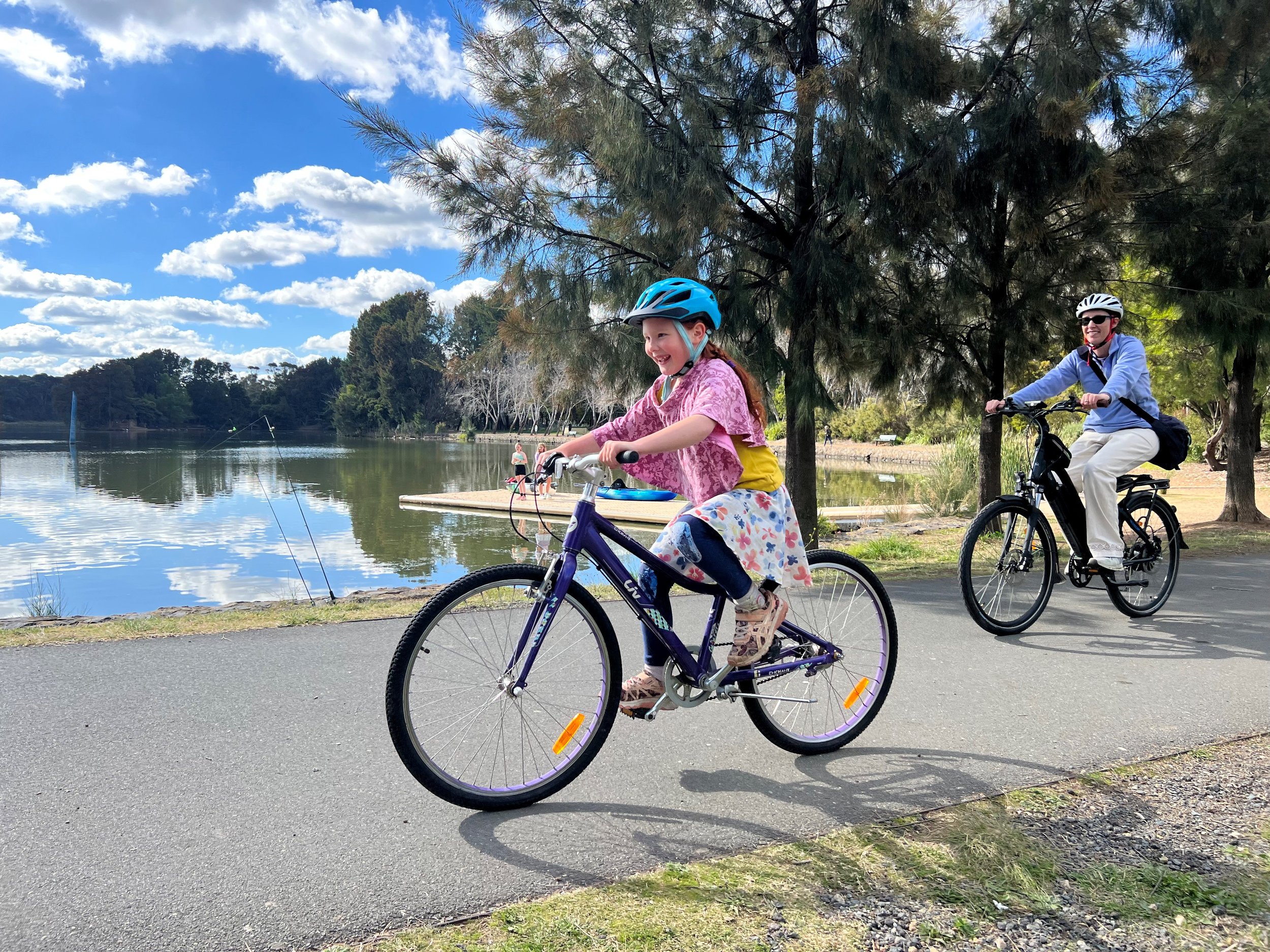 A child and adult riding beside a Canberra lake