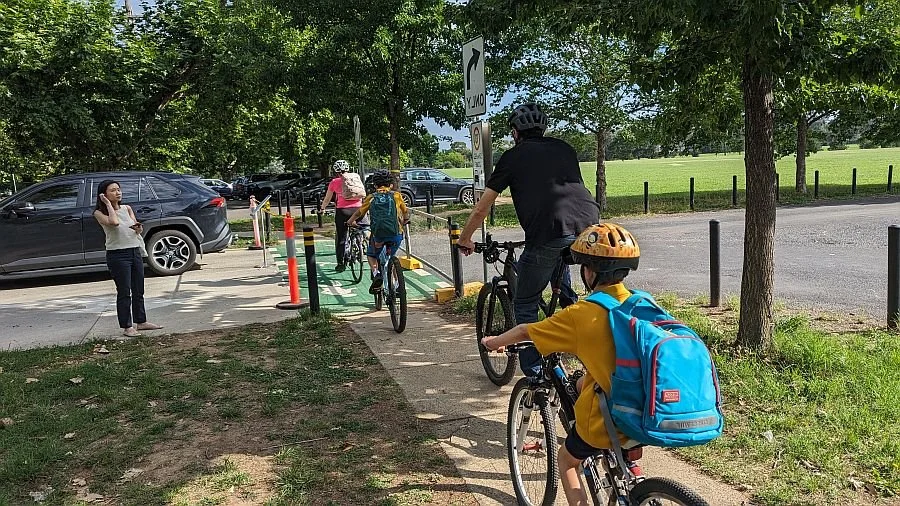 Children riding with the Lyneham school bike bus on a path beside the road
