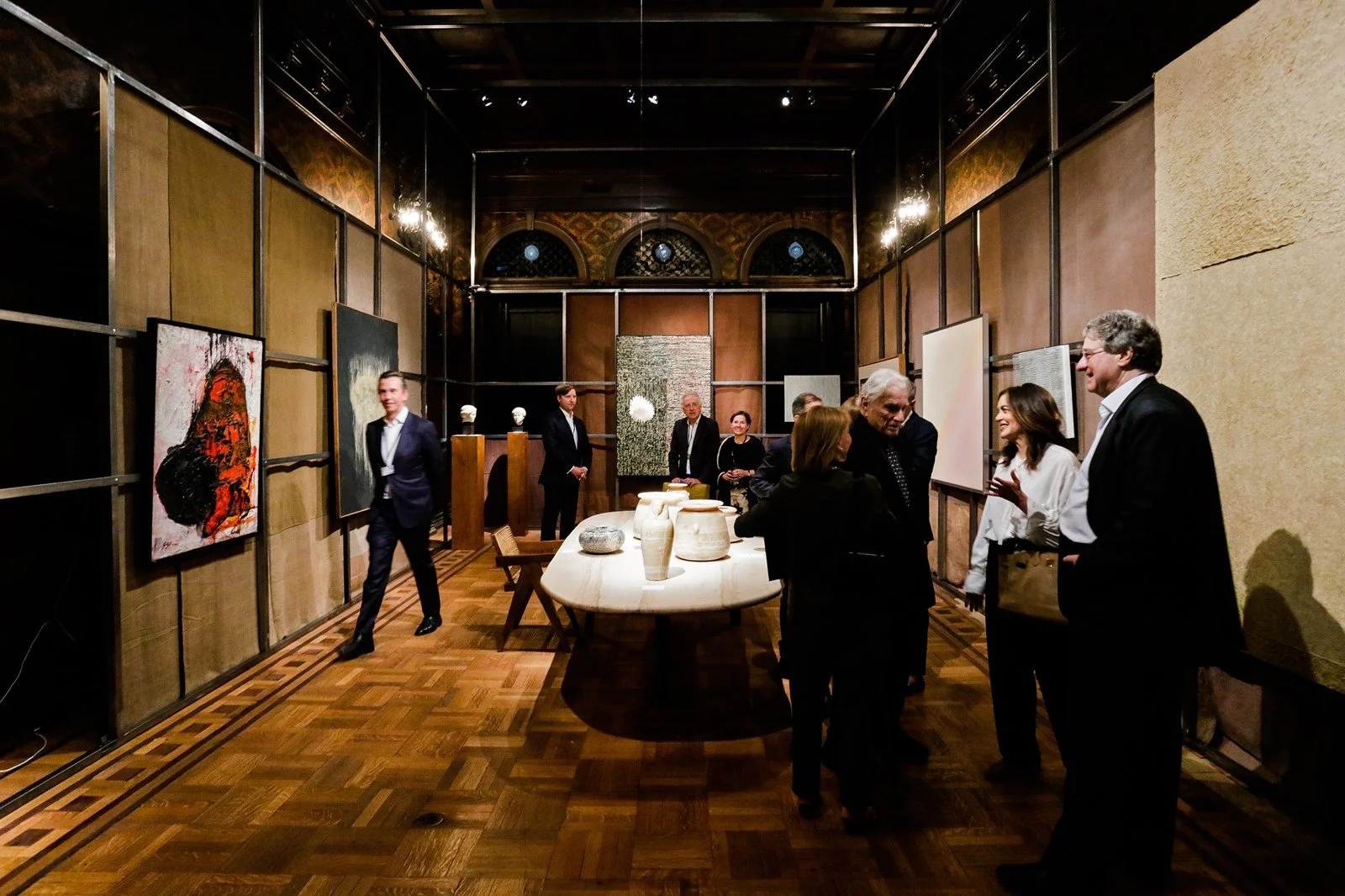 People gathered in an art gallery with paintings and sculptures, engaging in conversation.