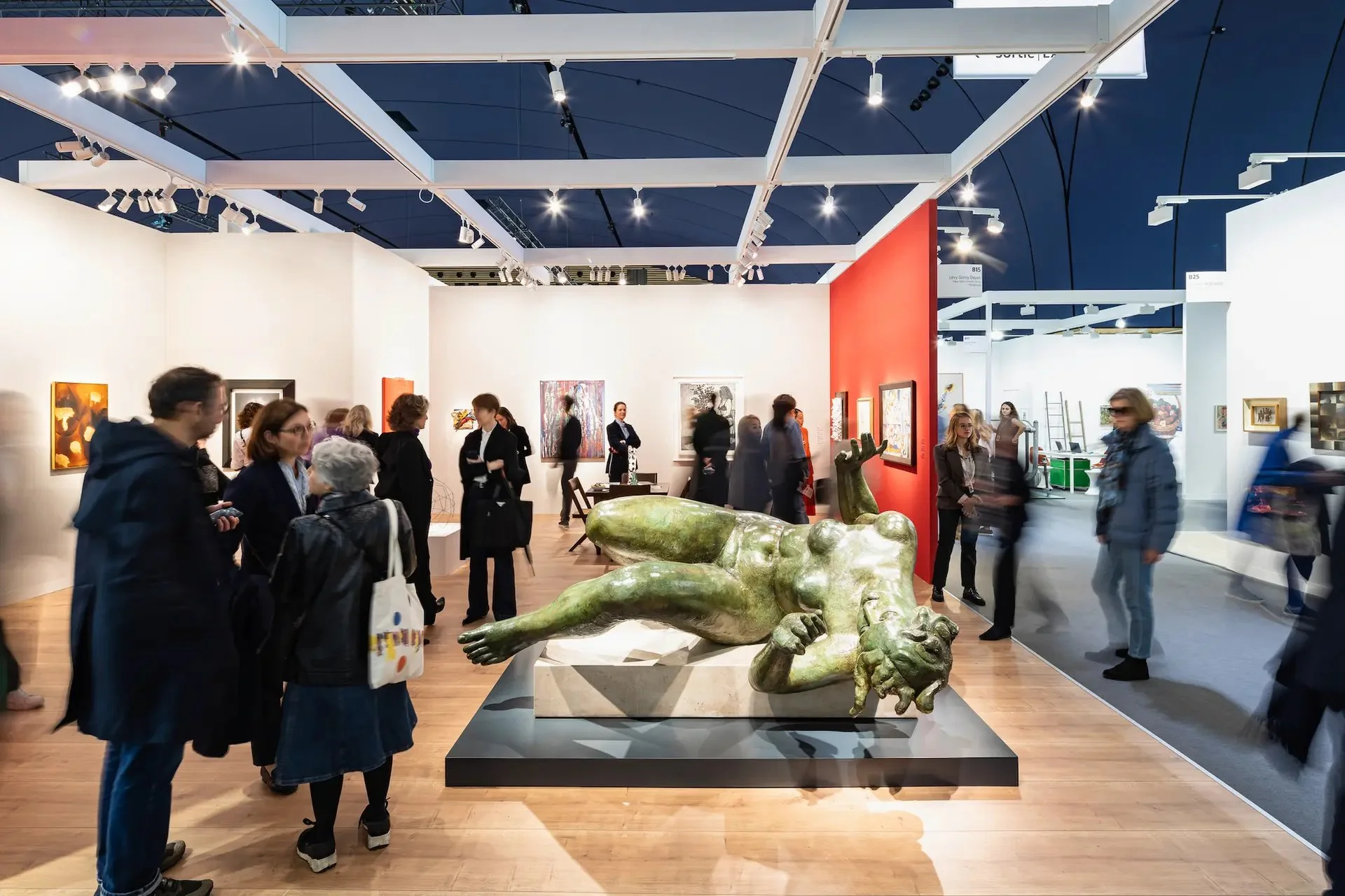 Art gallery with large green sculpture and people viewing artwork