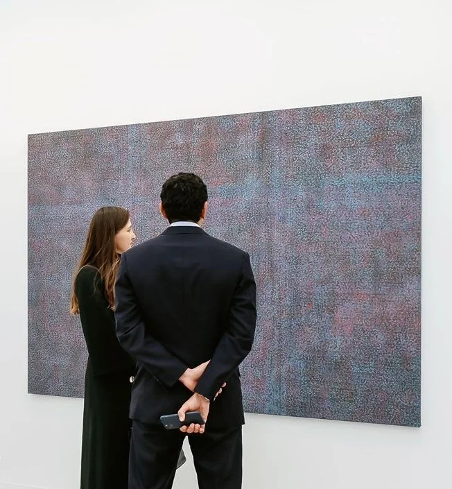 Two people viewing abstract artwork in a gallery