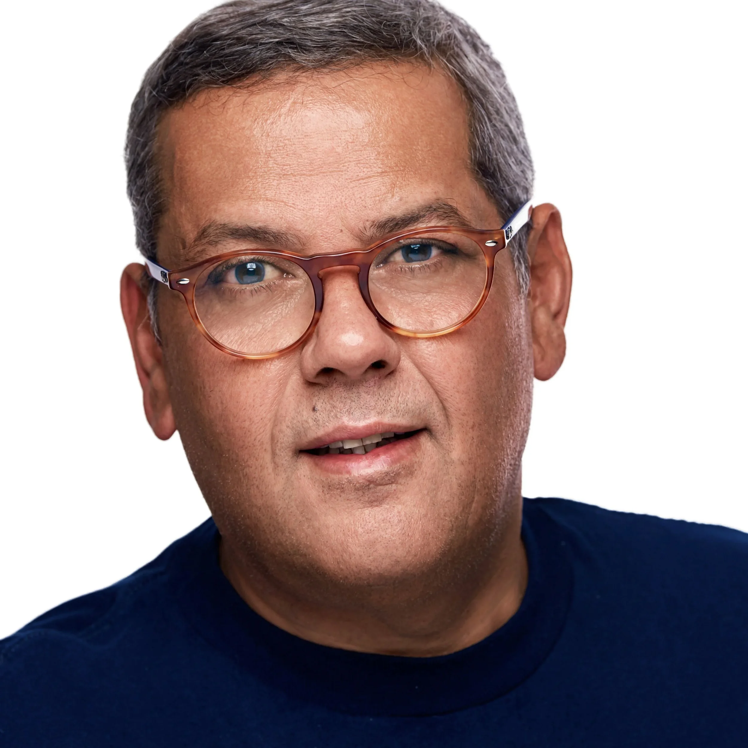 Amr Younis the photographer close-up wearing round tortoiseshell glasses, a navy blue shirt, and looking directly at the camera against a plain white background.