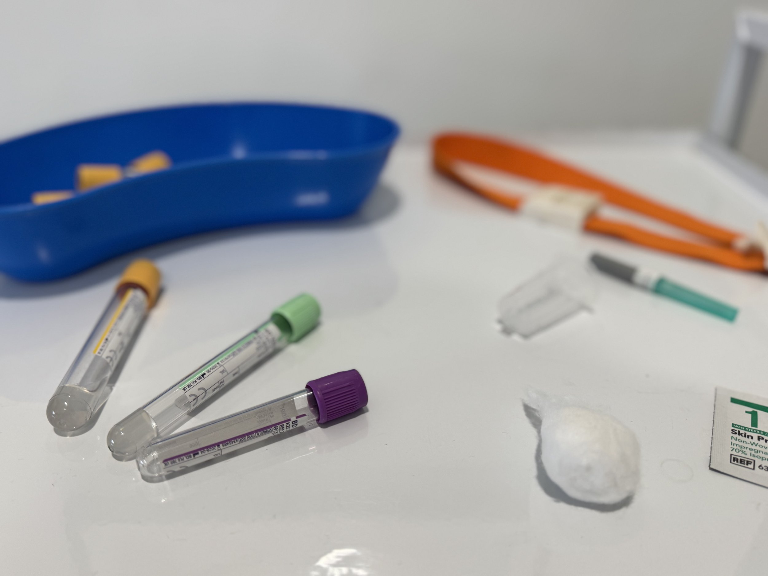 Medical test tubes and blood sample containers with colored caps on a white surface